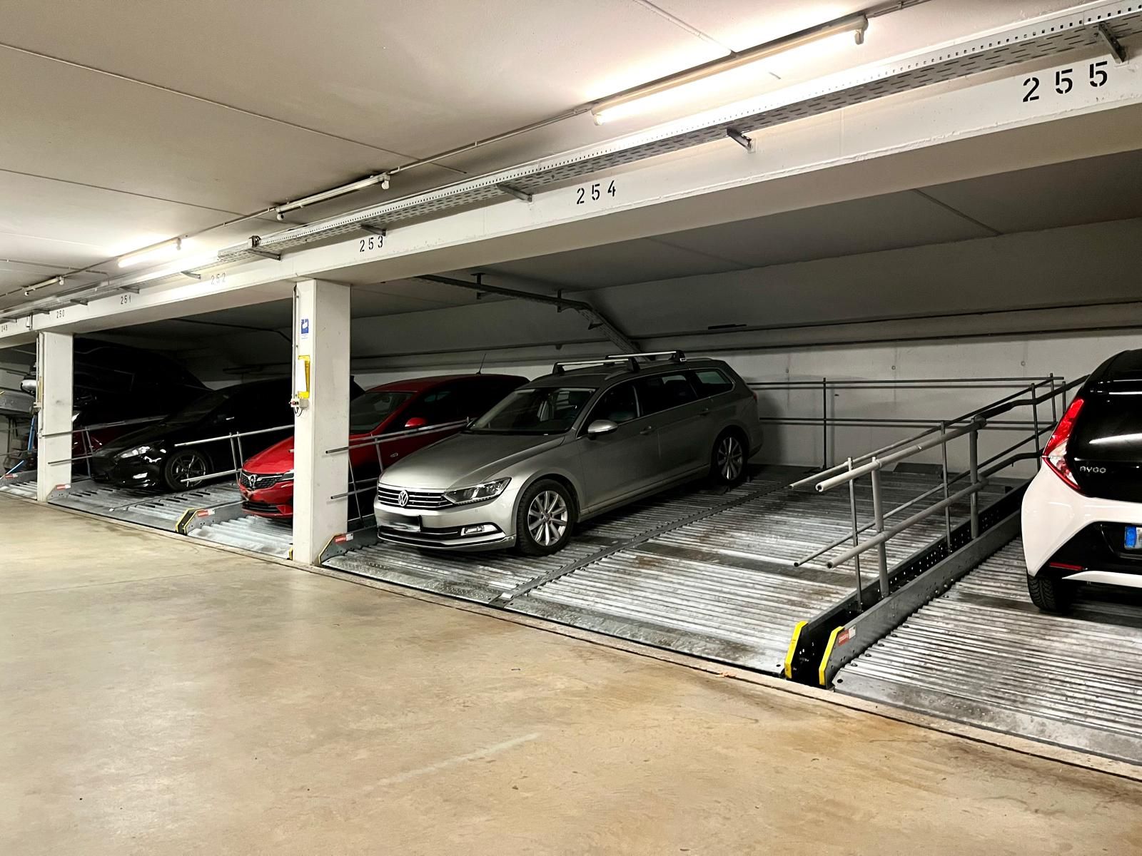 Mehrere Autos parken nebeneinander in einer Tiefgarage auf nummerierten Stellplätzen.