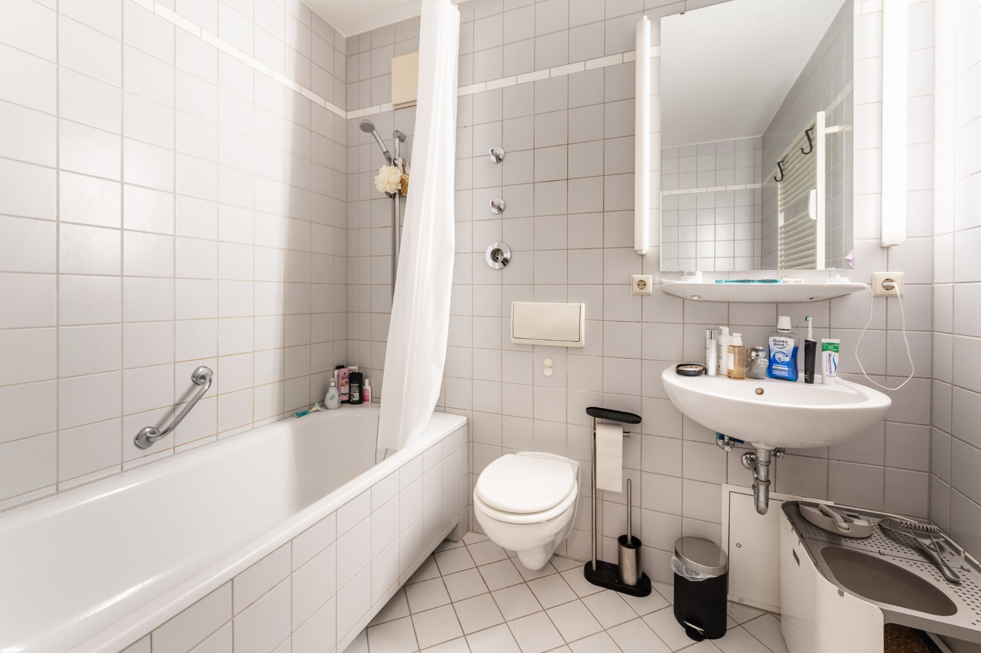 Helles Badezimmer mit Badewanne, Dusche, WC, Waschbecken und Spiegel.