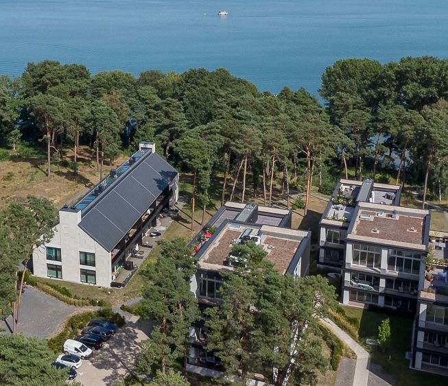 Mehrere moderne Wohngebäude mit Balkonen, umgeben von Bäumen in Seenähe.