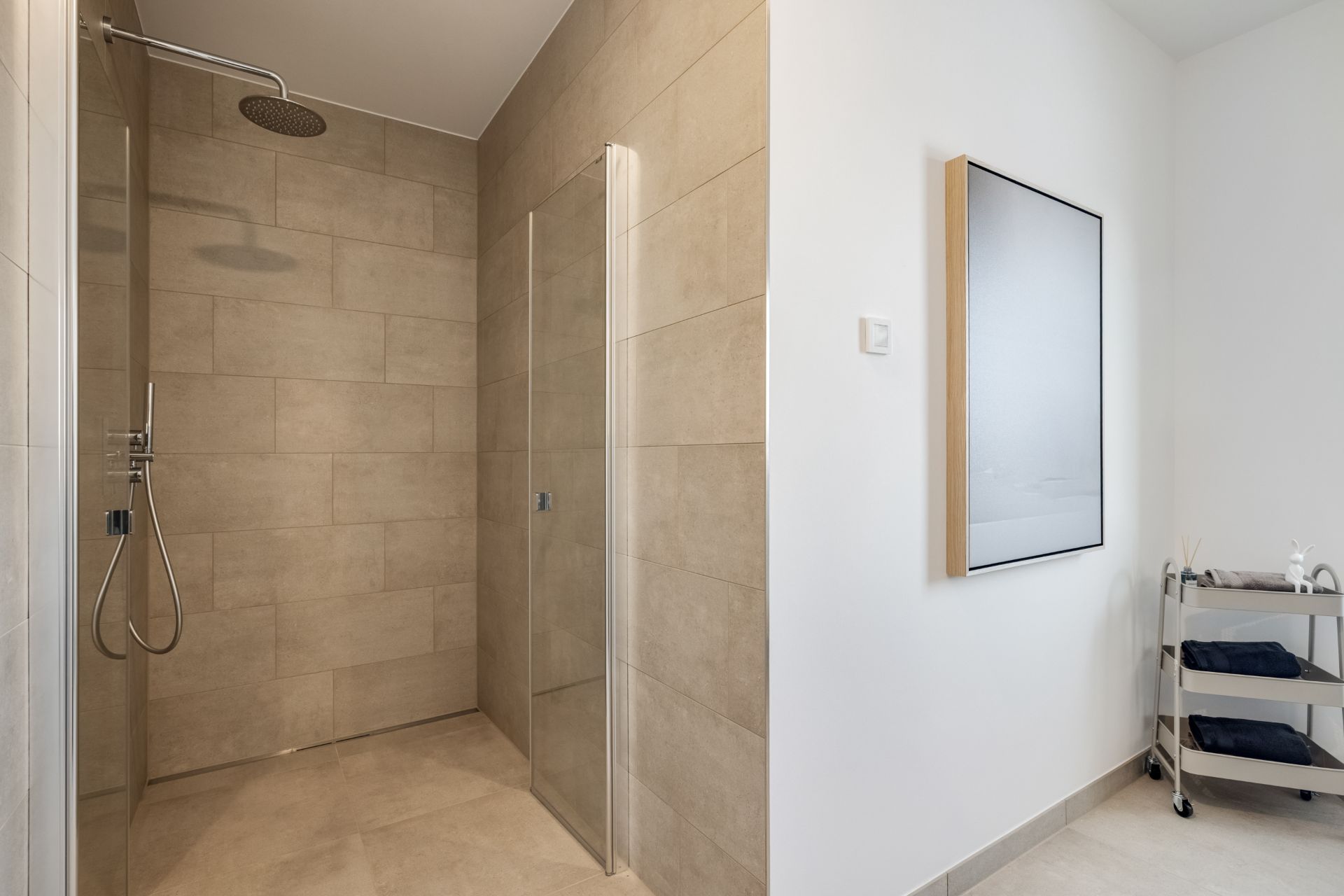 Modernes Badezimmer mit begehbarer Dusche, Spiegel und Handtuchwagen.