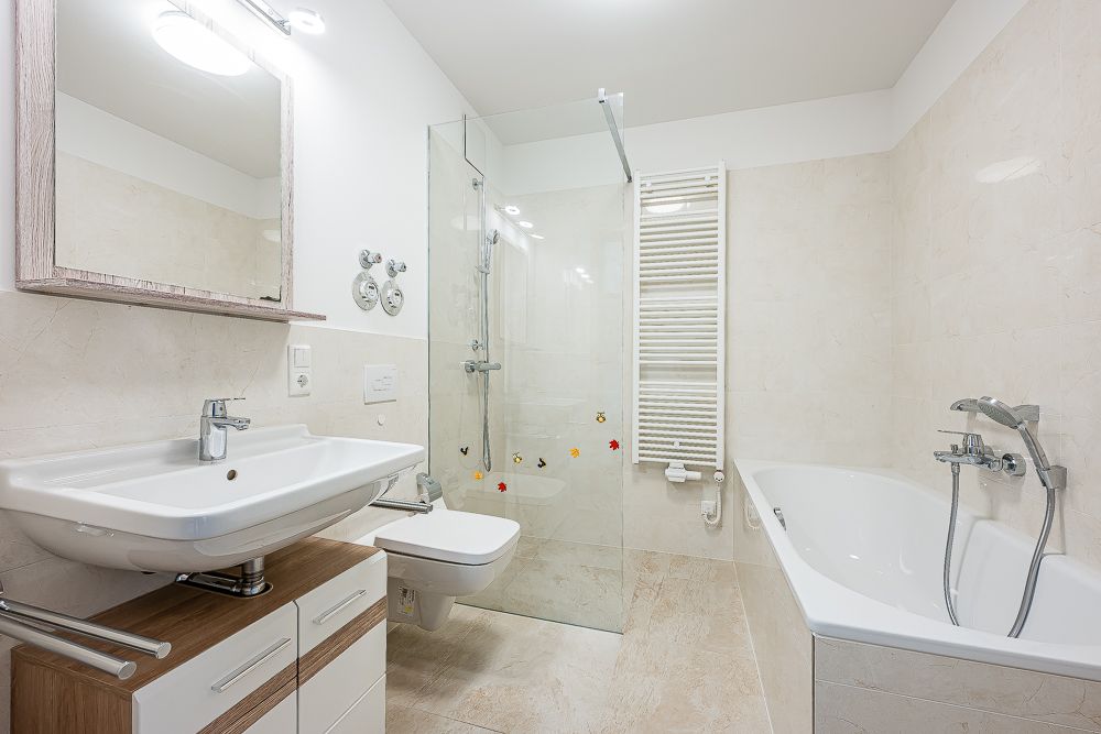 Modernes Badezimmer mit Waschbecken, Spiegel, Toilette, Dusche und Badewanne.
