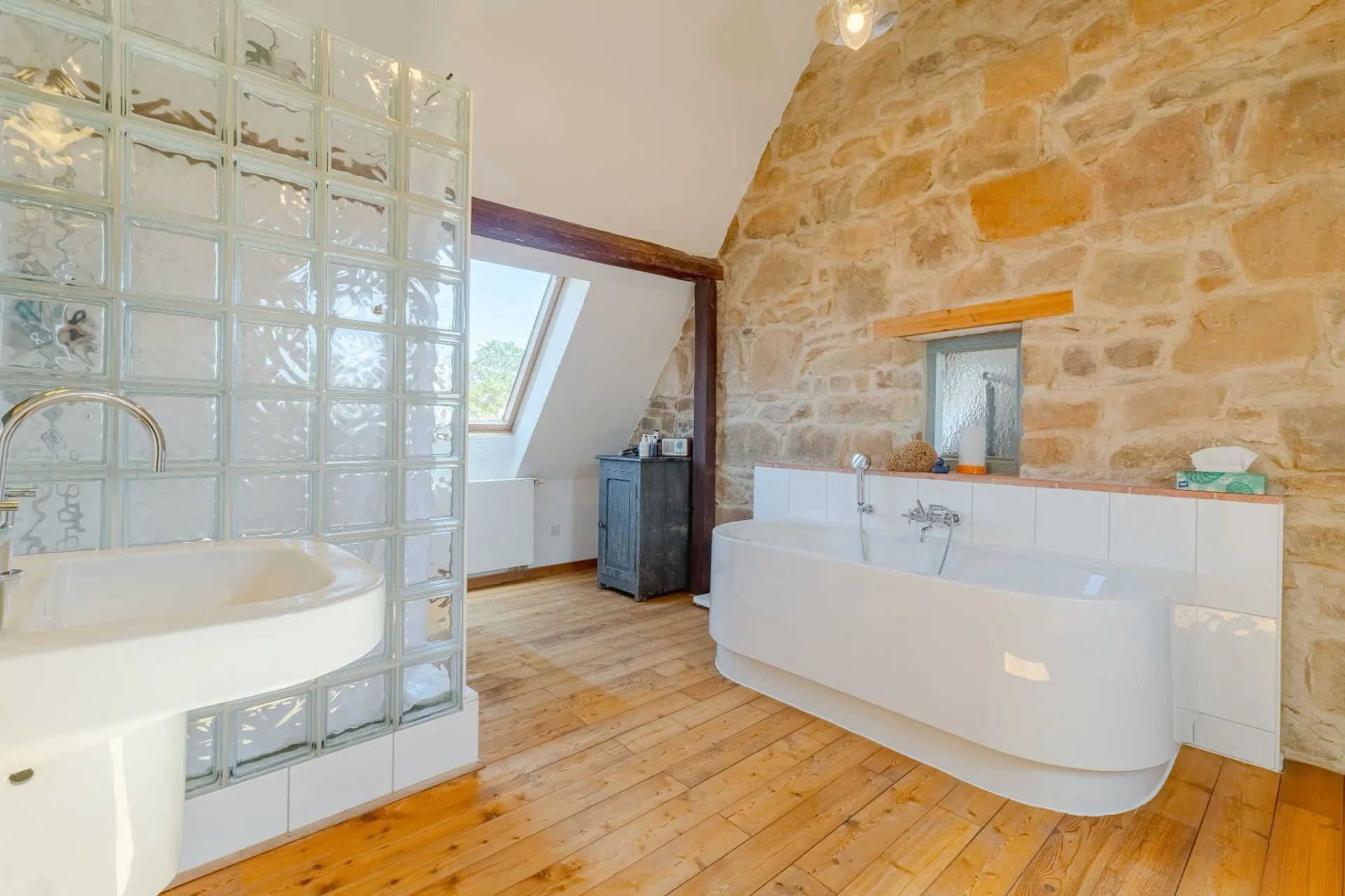 Helles Badezimmer mit freistehender Badewanne, Glasbaustein-Dusche und Holzboden.