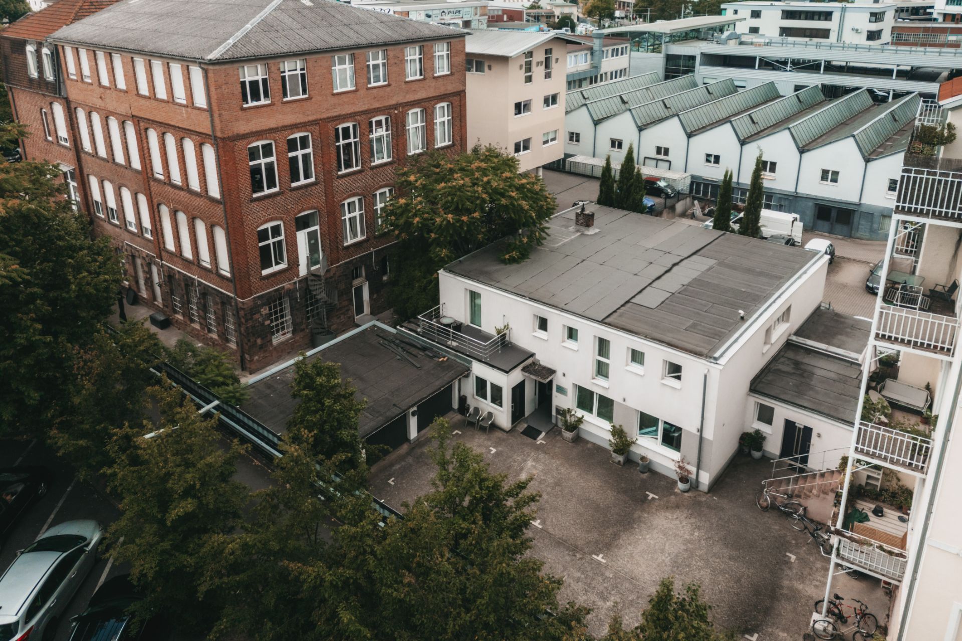 Innenhof mit weißen Wohngebäuden und Bäumen, umgeben von weiteren Häusern.