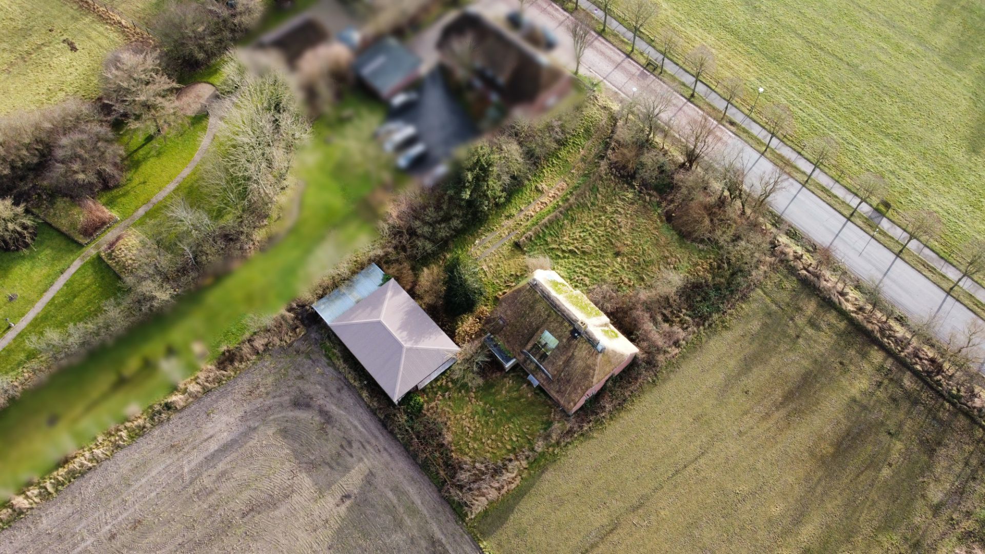 Luftaufnahme eines Einfamilienhauses mit Nebengebäude und Garten, umgeben von Feldern und Bäumen.