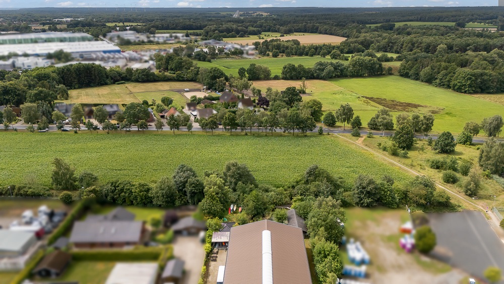 Luftaufnahme von Wohnhäusern und Feldern auf dem Land mit vielen Bäumen und Wiesen.