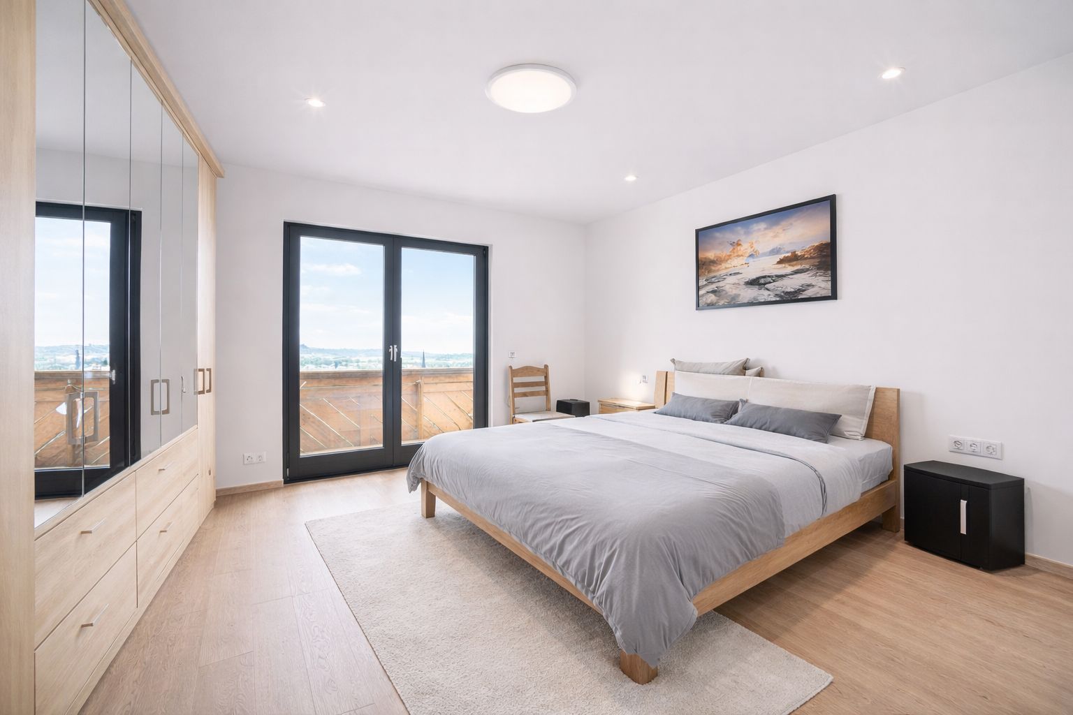 Helles Schlafzimmer mit Doppelbett, Kleiderschrank, Nachttischen und Fenstertür zum Balkon.