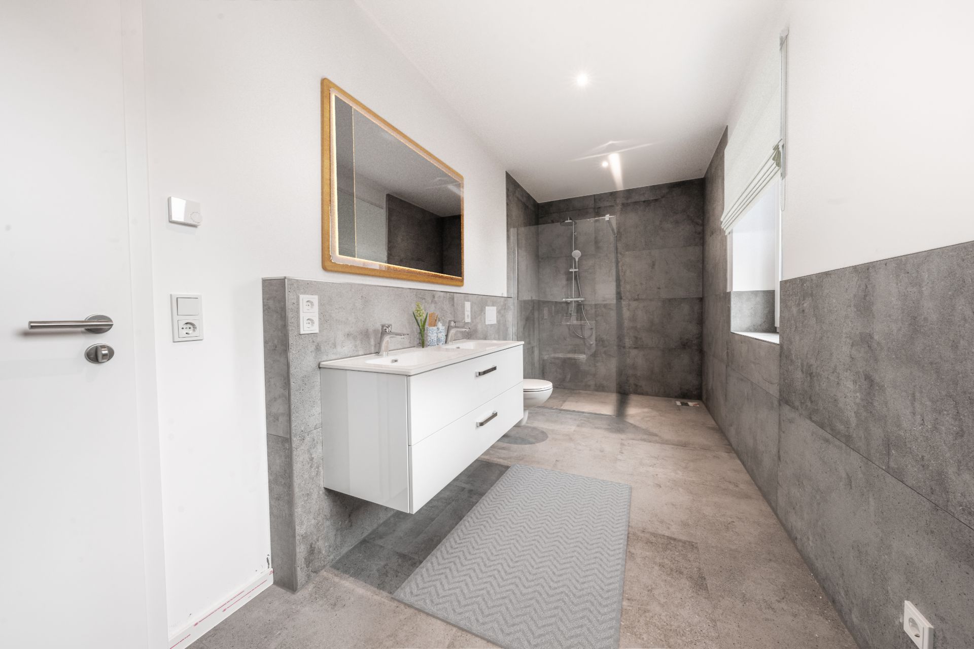Modernes Badezimmer mit Waschtisch, großem Spiegel und ebenerdiger Dusche.