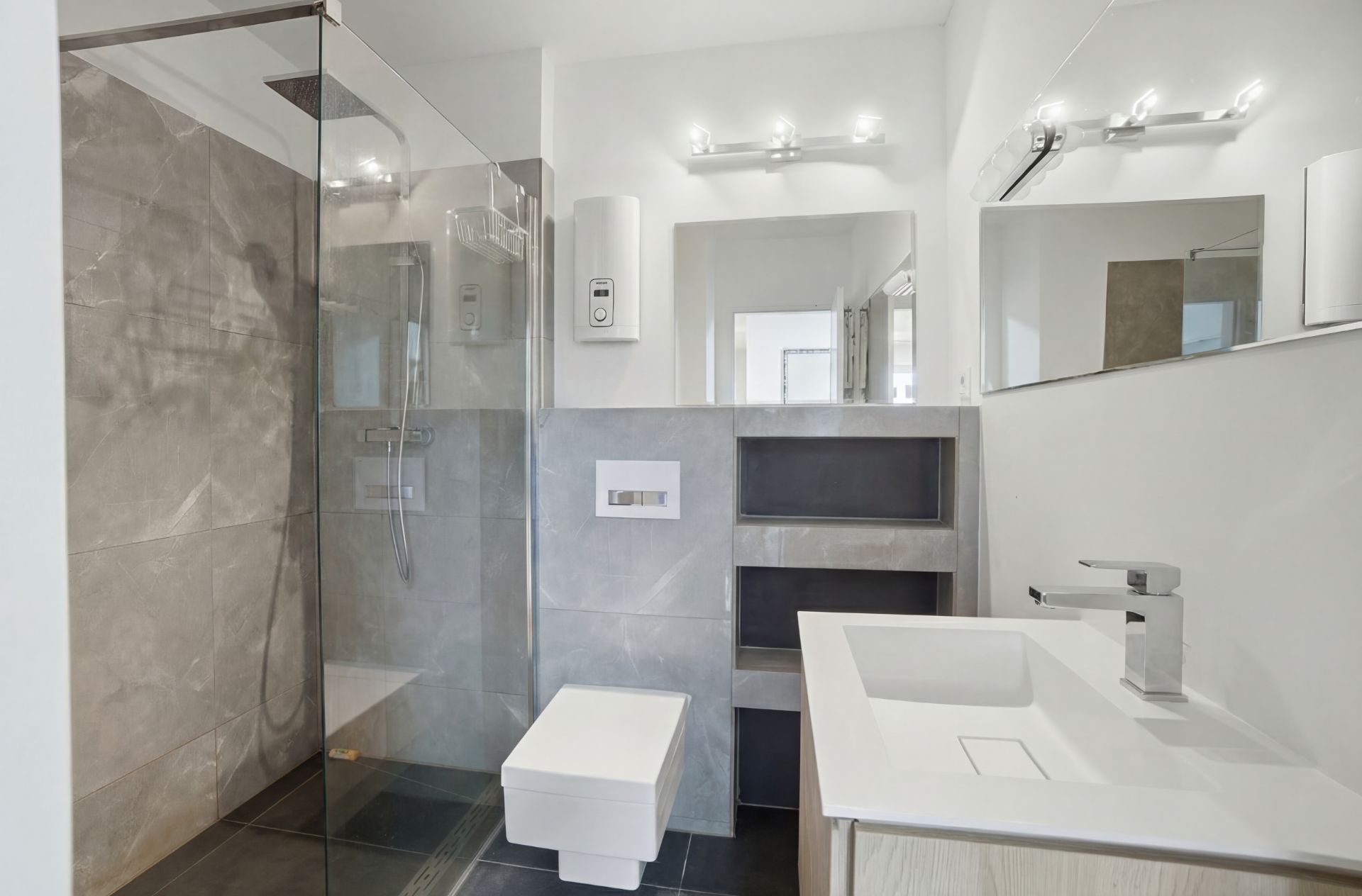 Modernes Badezimmer mit Glasdusche, Wandtoilette, Waschbecken und großem Spiegel.