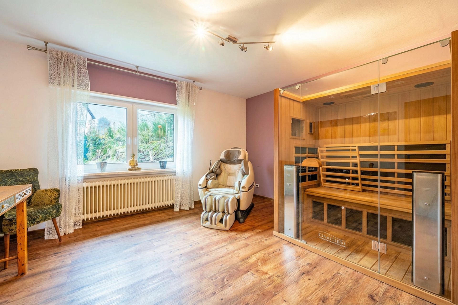 Helles Zimmer mit Massagesessel, großer Glas-Sauna und Fenster mit Blick auf Garten.