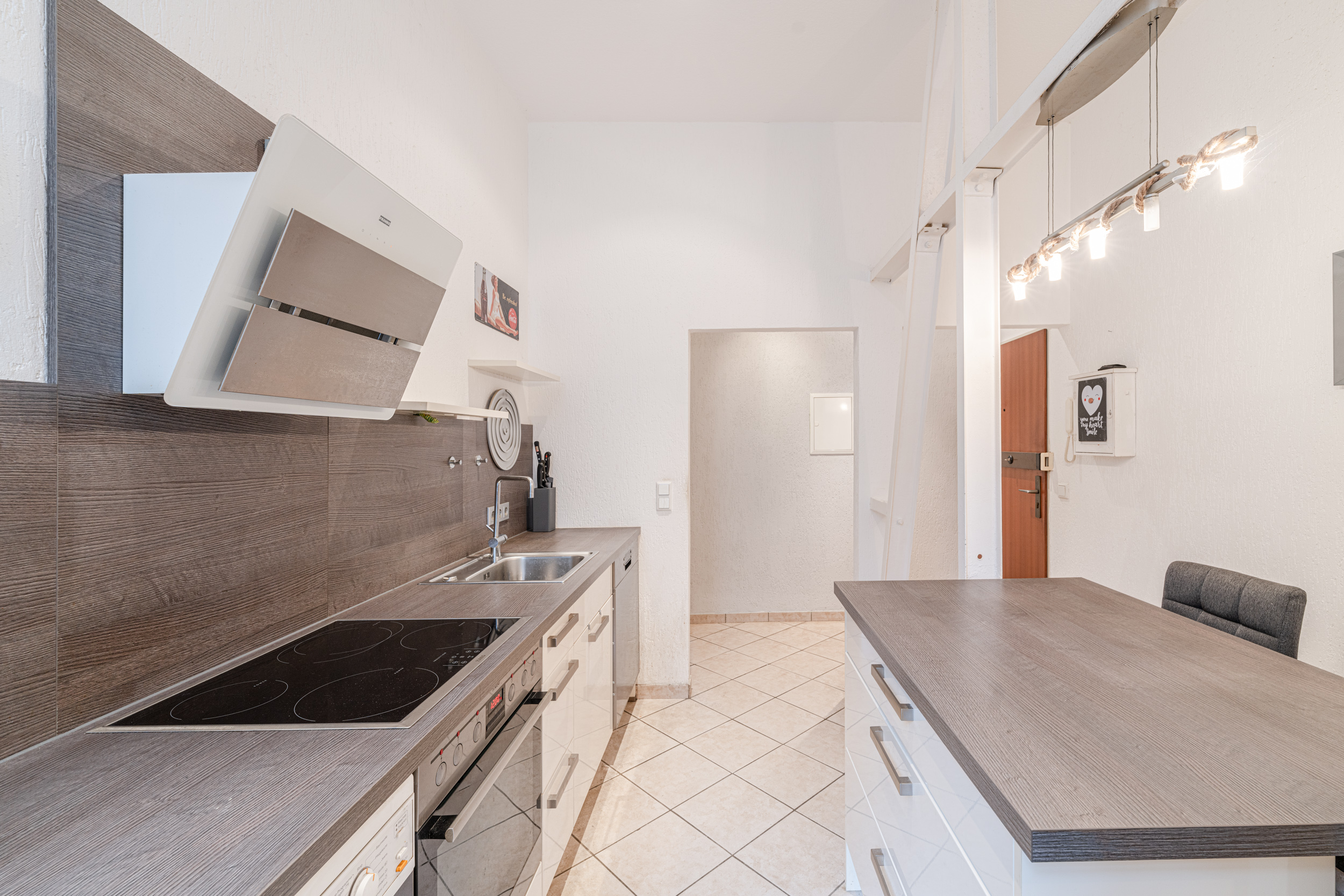 Moderne Küche mit Elektroherd, Spüle, Arbeitsfläche und Deckenbeleuchtung.