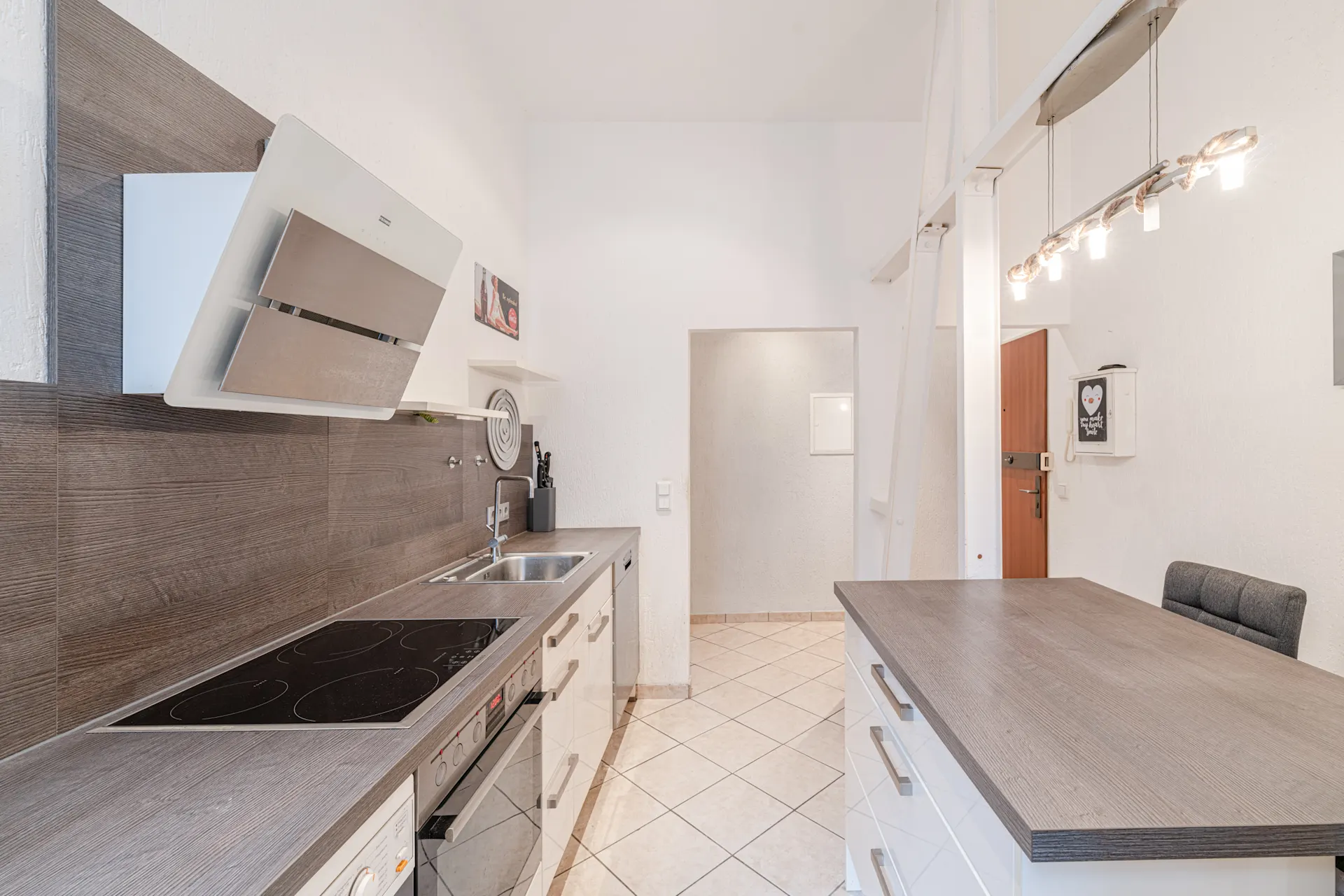 Moderne Küche mit Elektroherd, Spüle, Arbeitsfläche und Deckenbeleuchtung.