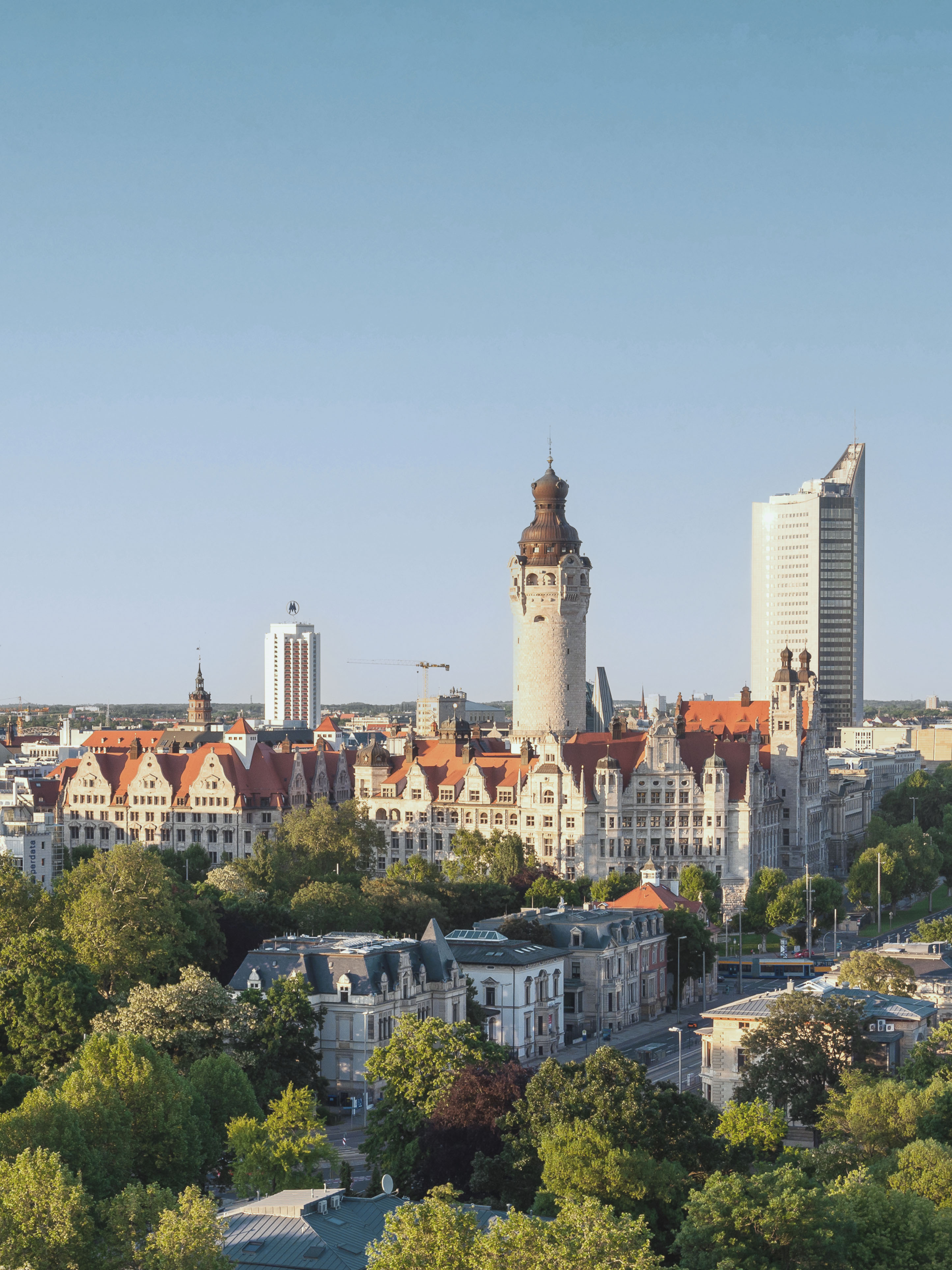 Blick auf eine Stadt mit historischen und modernen Gebäuden, umgeben von viel Grün.