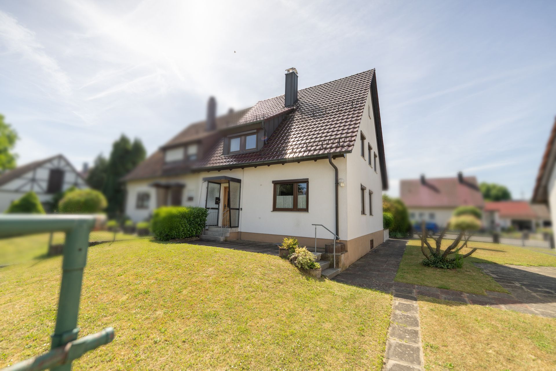 Einfamilienhaus mit Satteldach und gepflegtem Vorgarten an einem sonnigen Tag.
