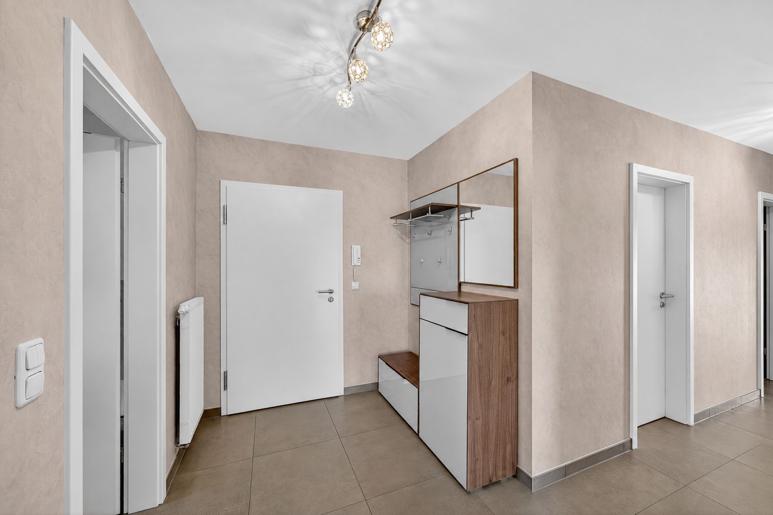 Heller Flur mit mehreren Türen, Garderobe und Spiegel.
