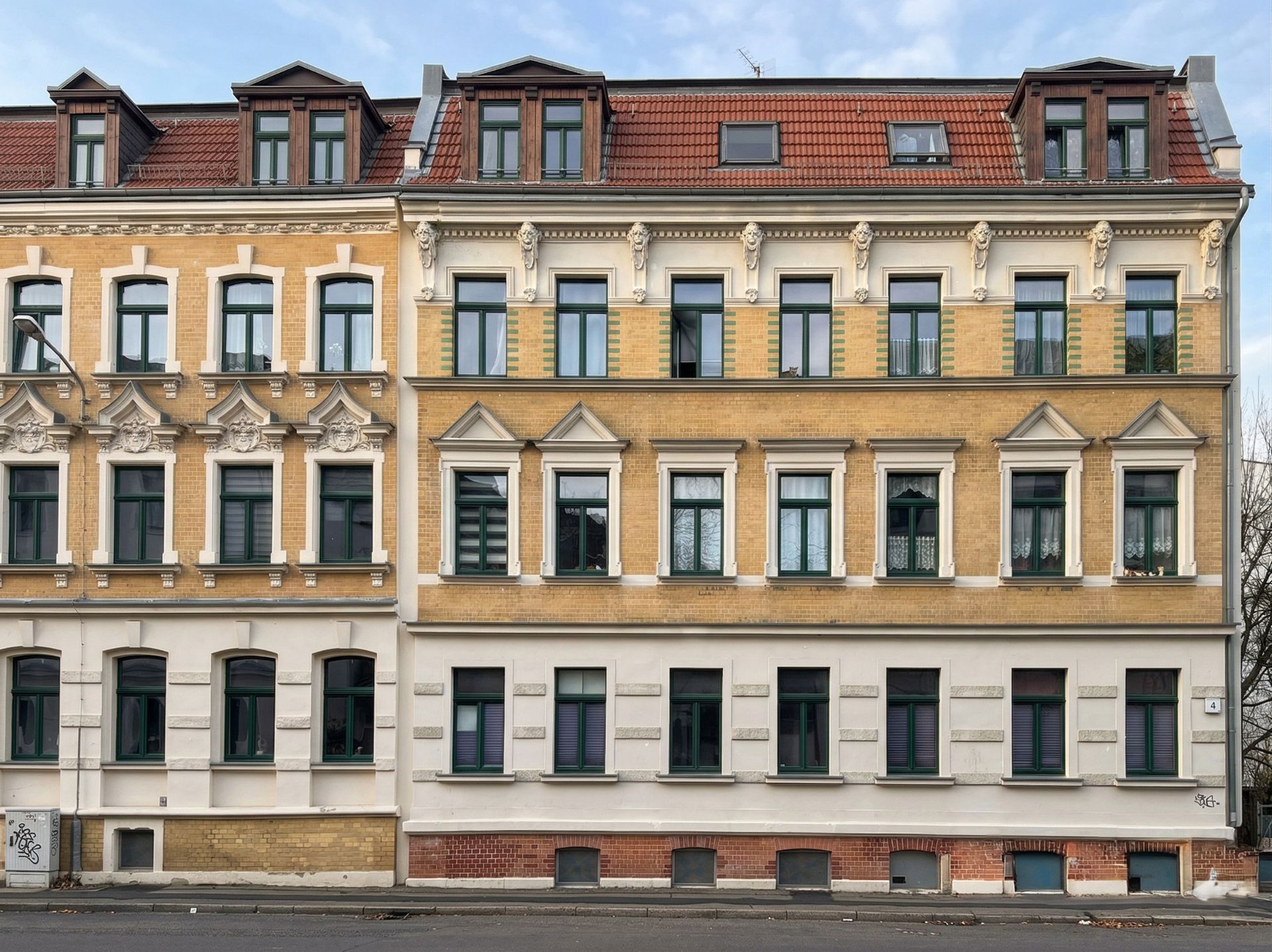 Fassade eines mehrstöckigen Wohnhauses mit vielen Fenstern und rotem Dach.