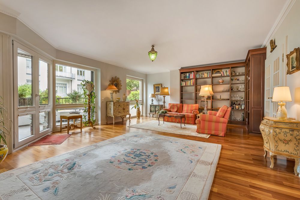 Großes, helles Wohnzimmer mit Holzfußboden, Teppich, Sofa, Bücherregal und vielen Lampen.