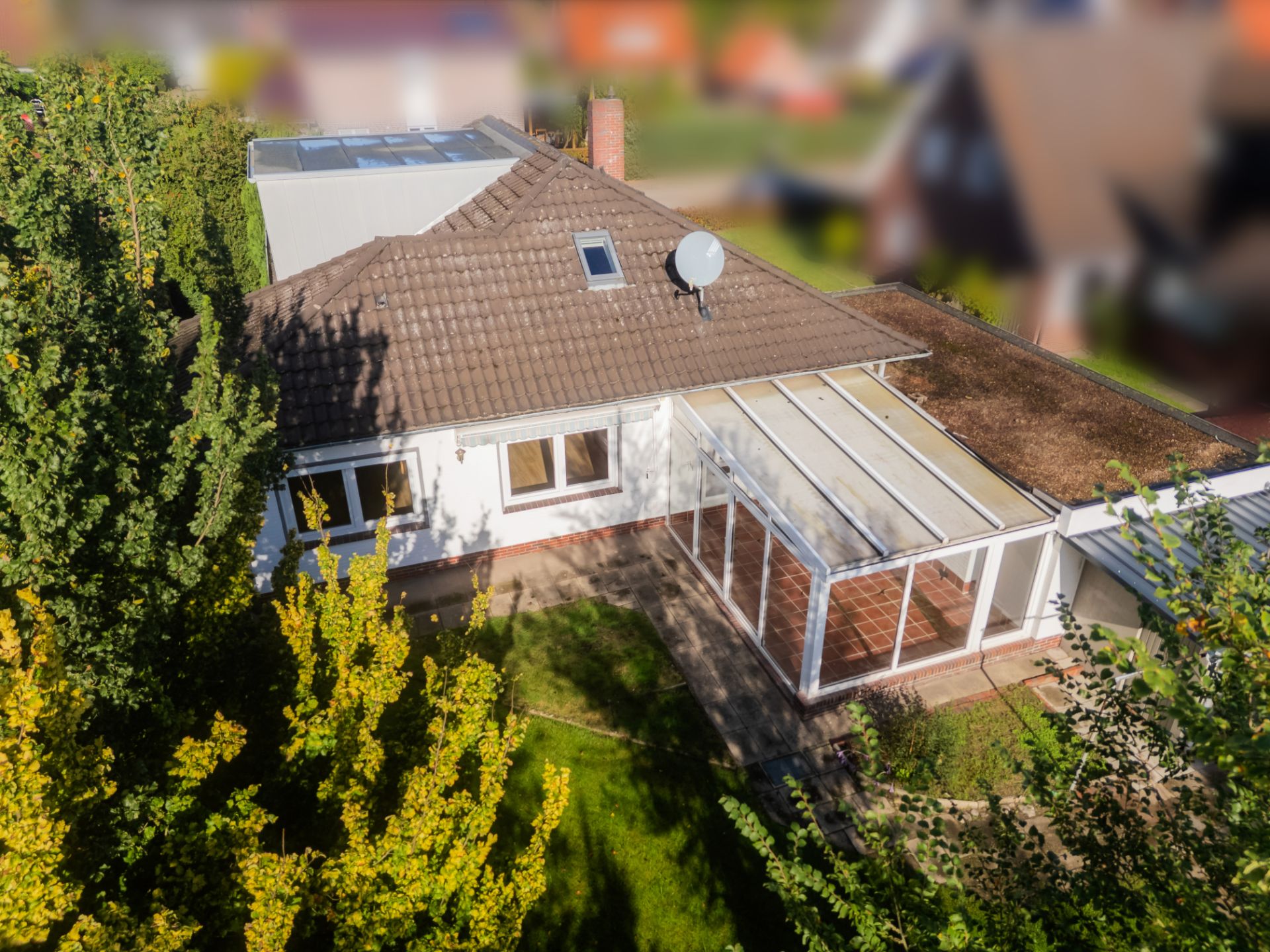 Luftaufnahme eines Einfamilienhauses mit Wintergarten und Garten.