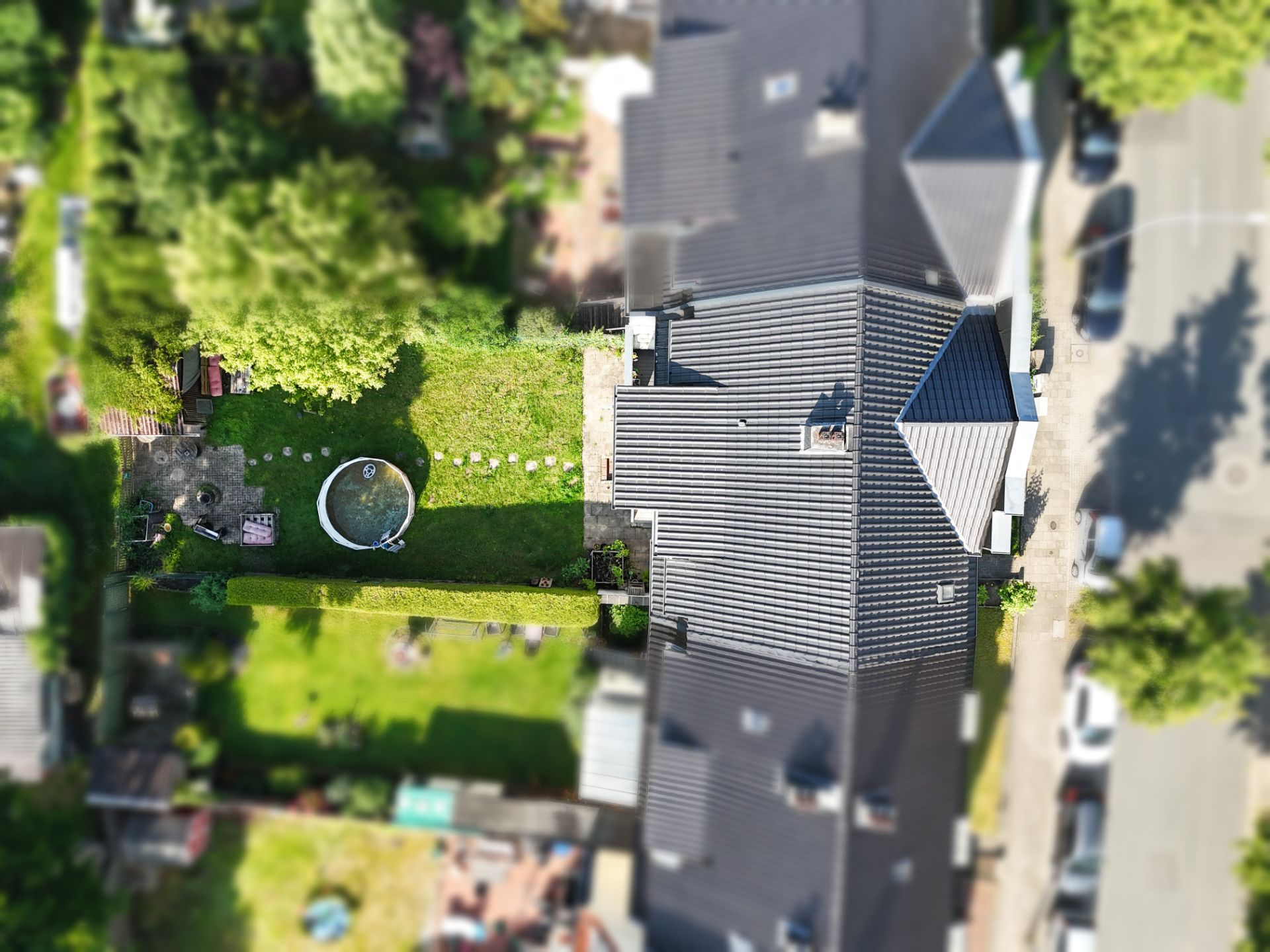 Luftaufnahme eines Hauses mit Garten, Rasenfläche und kleinem runden Pool.