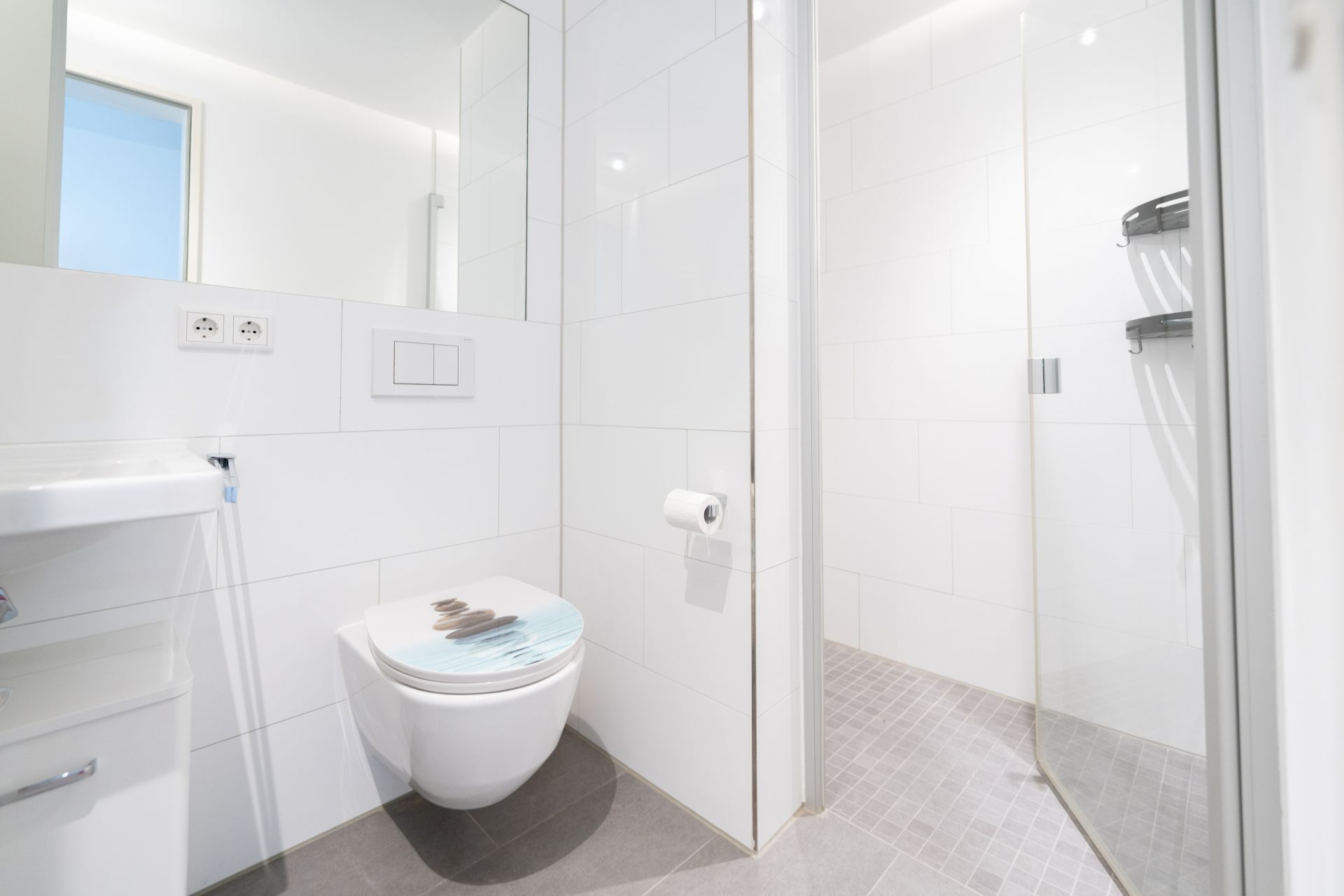 Modernes Bad mit Wandtoilette, Waschbecken und Glas-Duschkabine.