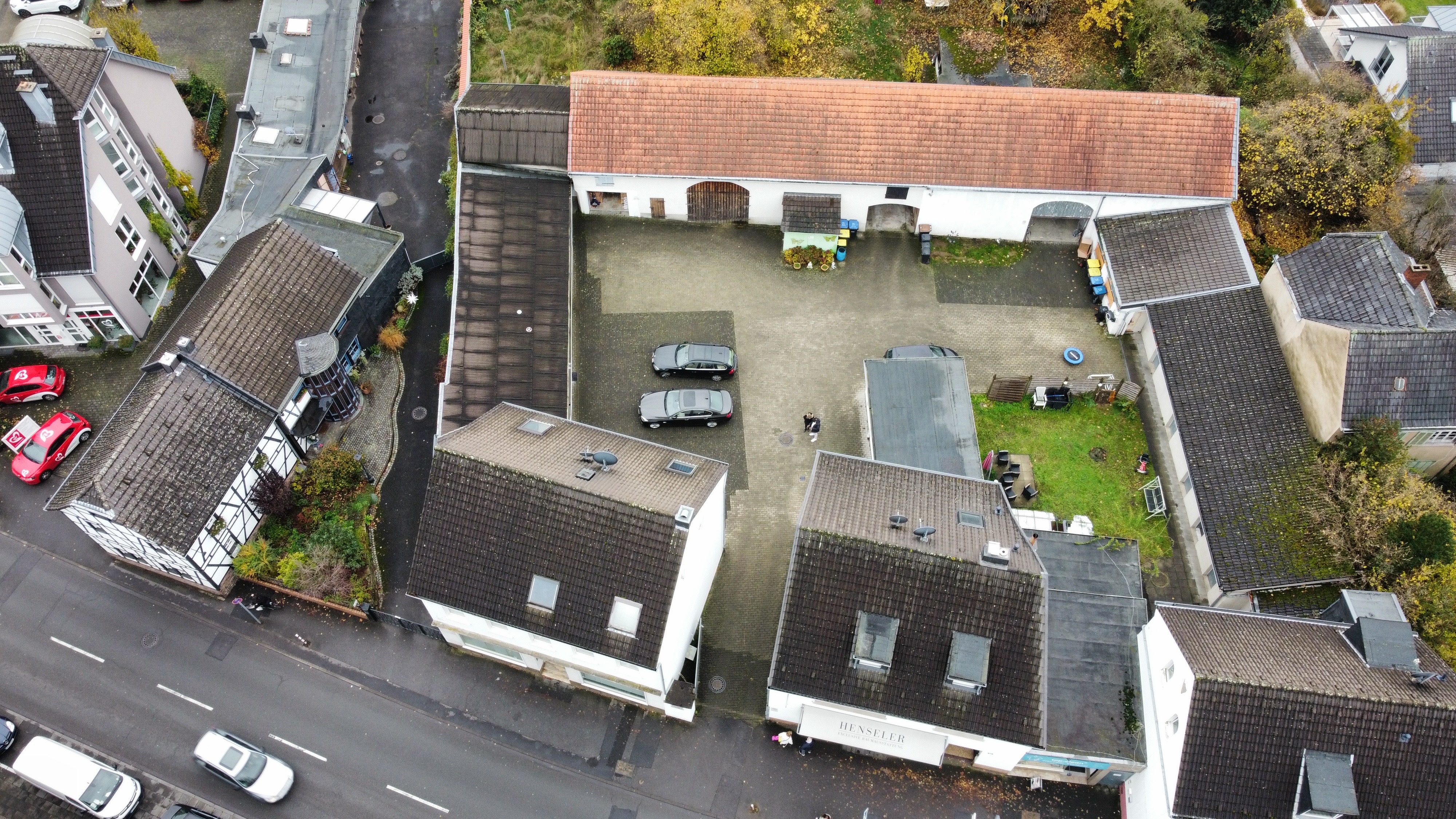 Luftaufnahme eines Innenhofs mit Autos, umgeben von Wohnhäusern und Garten.