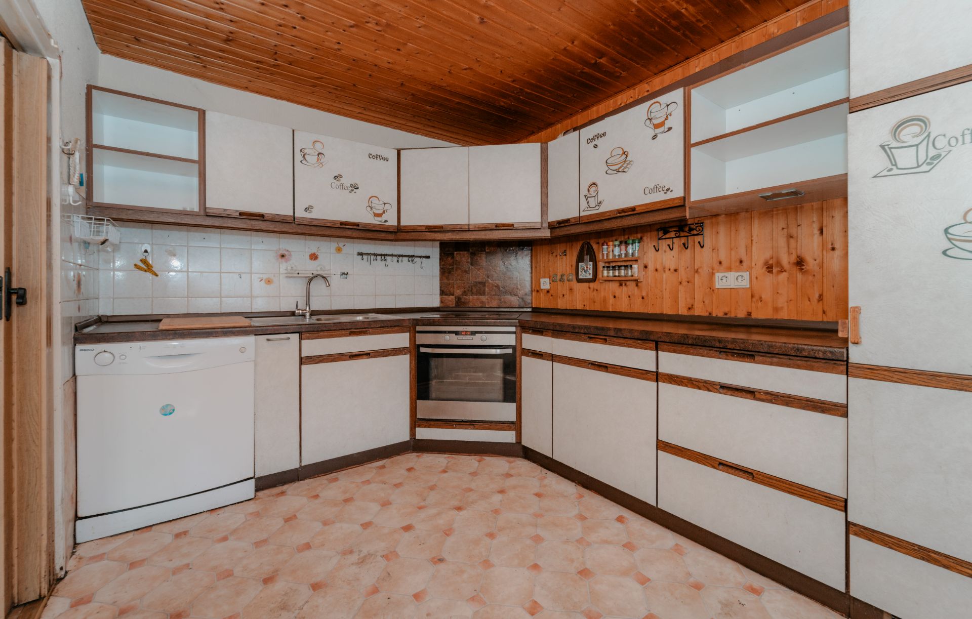 Küche mit weißen Schränken, Holzwand, Einbauofen und Geschirrspüler.