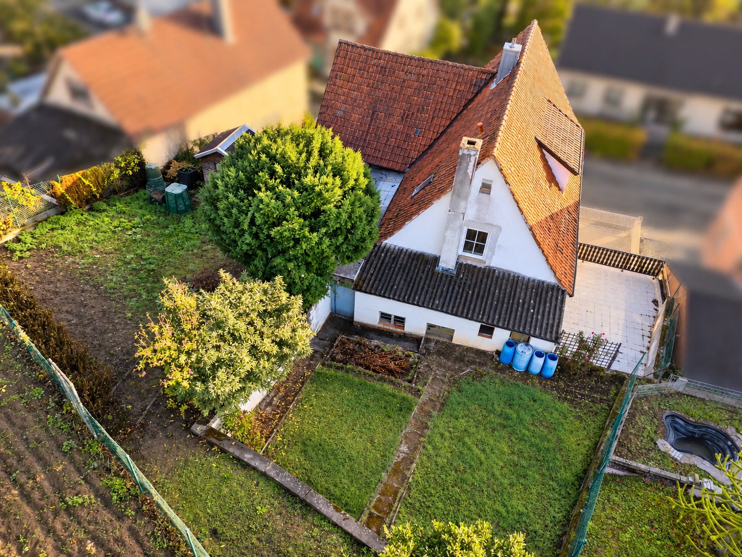 Luftaufnahme eines Einfamilienhauses mit Garten, mehreren Bäumen und Rasenfläche.