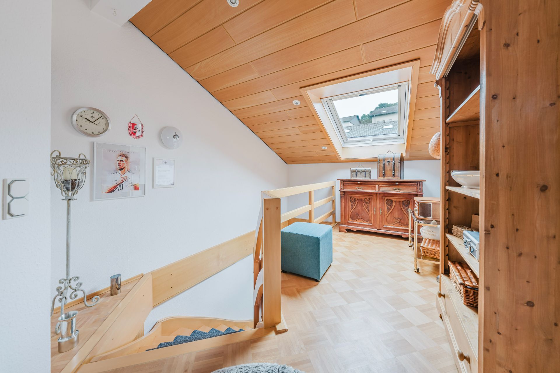 Heller Dachgeschossflur mit Holzdecke, Treppe, Sideboard, Regal und Dachfenster.