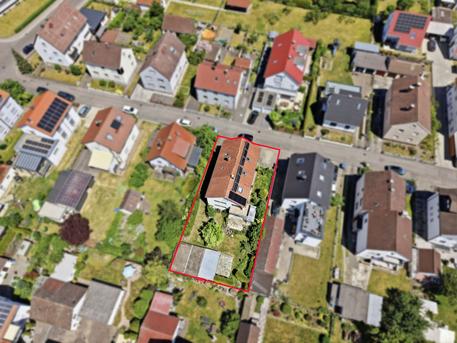 Luftaufnahme eines Wohnhauses mit Garten, Grundstück durch rote Linie markiert.