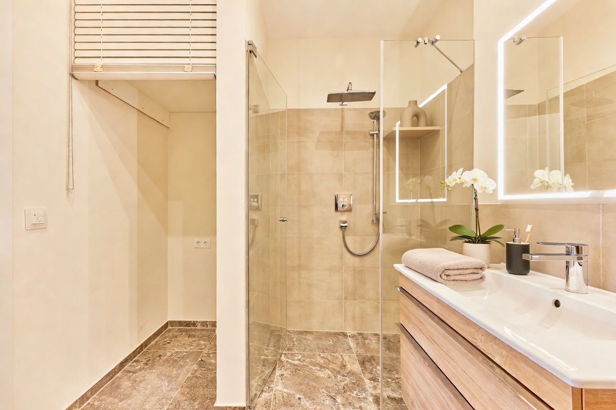 Modernes Badezimmer mit Dusche, großem Spiegel, Waschbecken und Holzkommode.