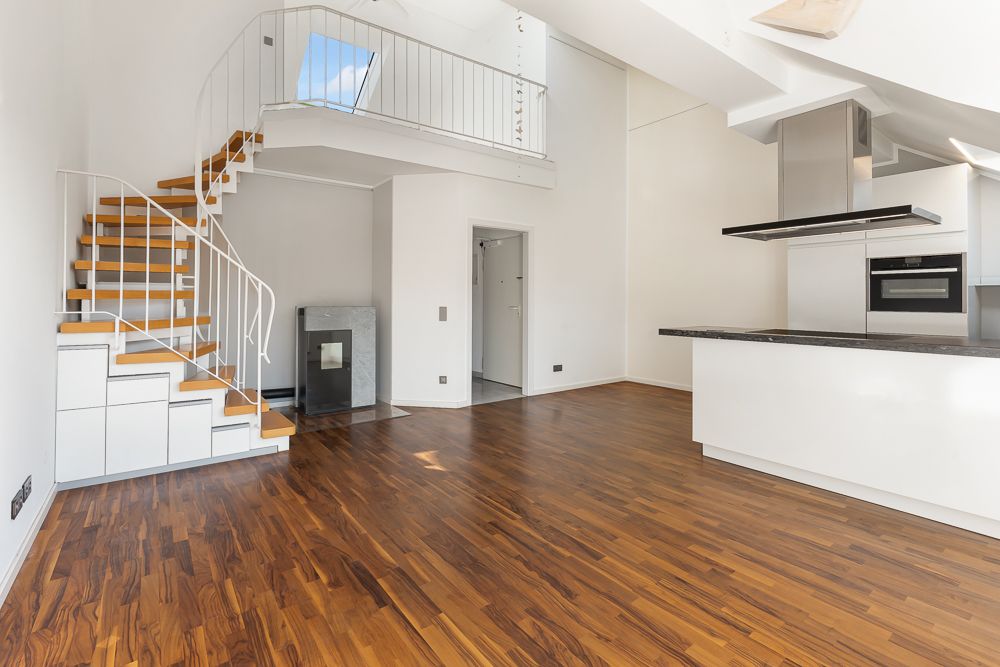 Modernes Wohnzimmer mit Holzfußboden, offener Küche und Treppe zu einer Galerie.