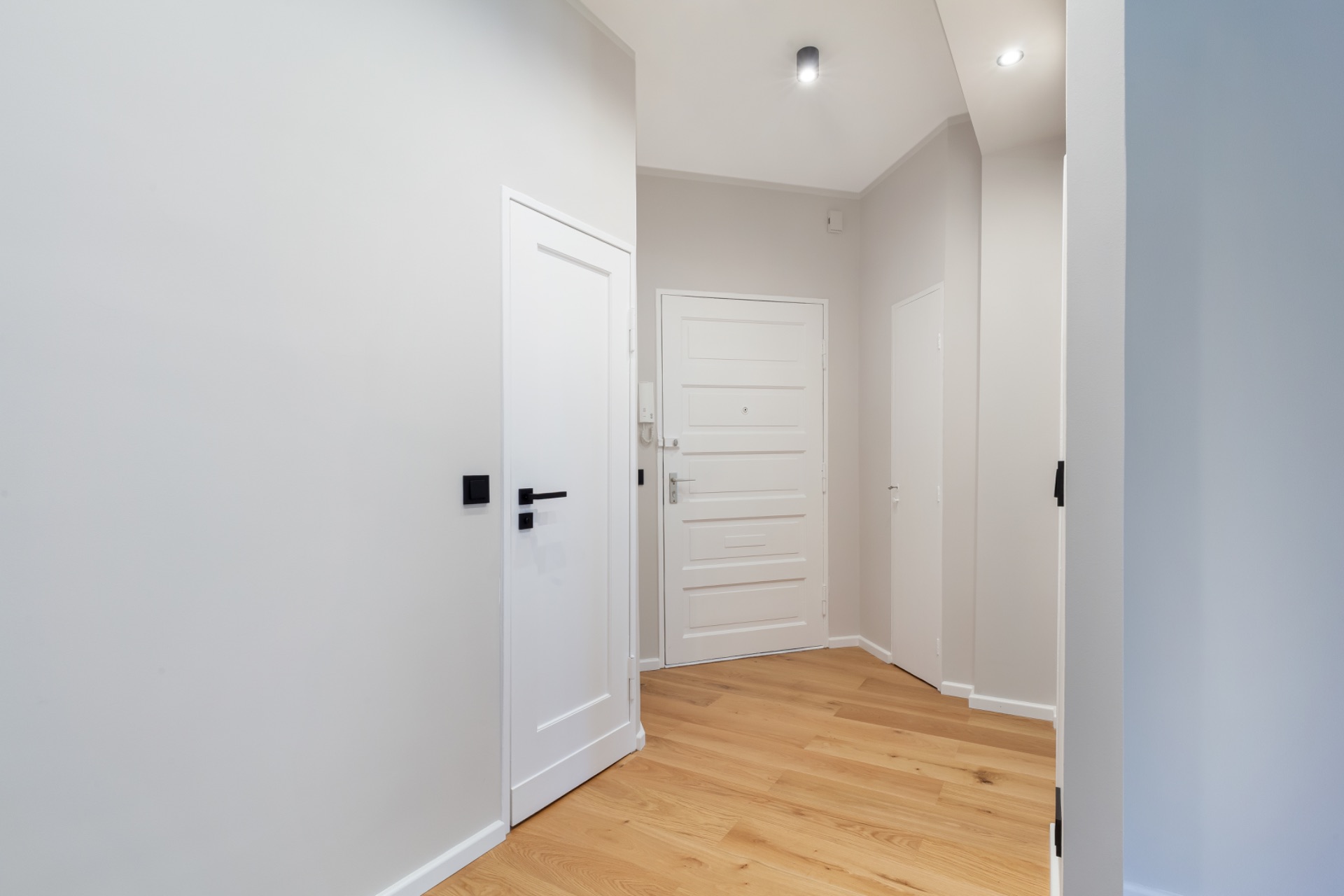 Heller Flur mit Holzboden und weißen Türen in einer Wohnung.