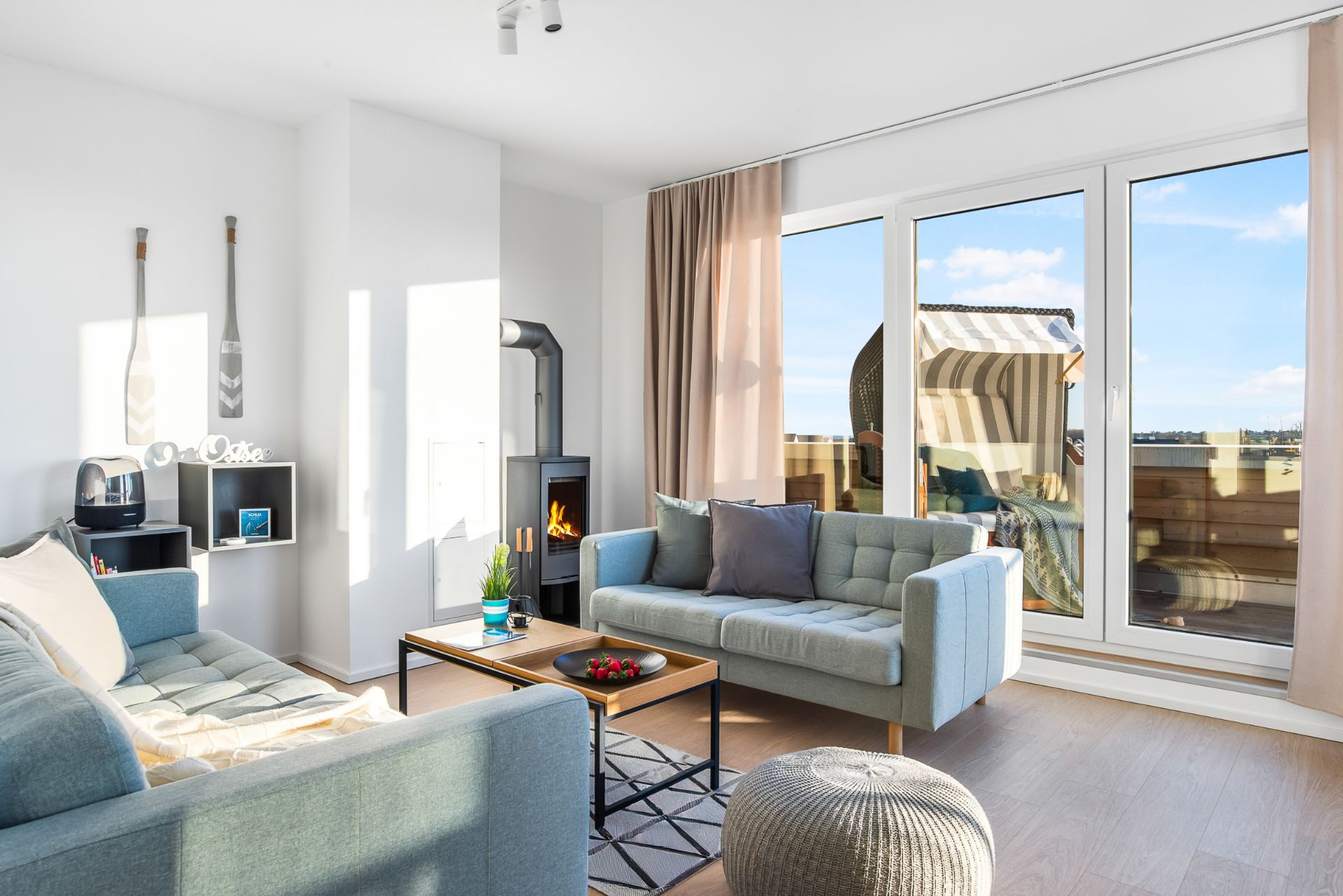 Helles Wohnzimmer mit zwei Sofas, Kamin, Couchtisch und großem Fenster zum Balkon.