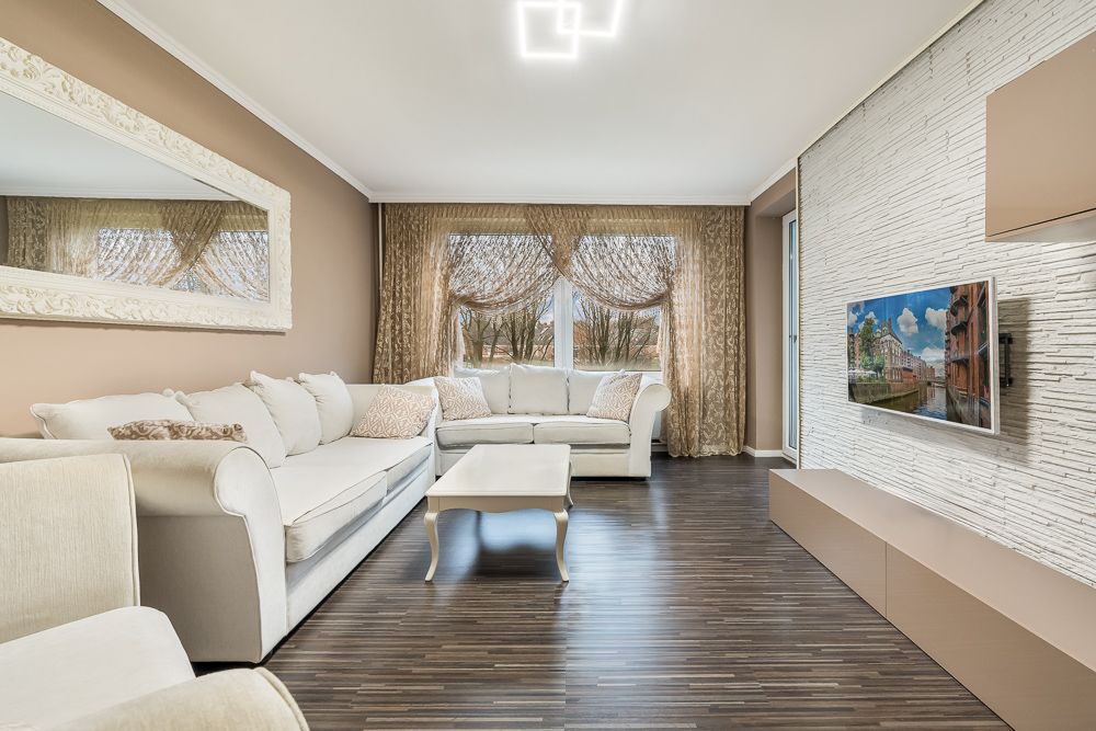 Modernes Wohnzimmer mit zwei weißen Sofas, Couchtisch und Fernseher an einer hellen Wand.