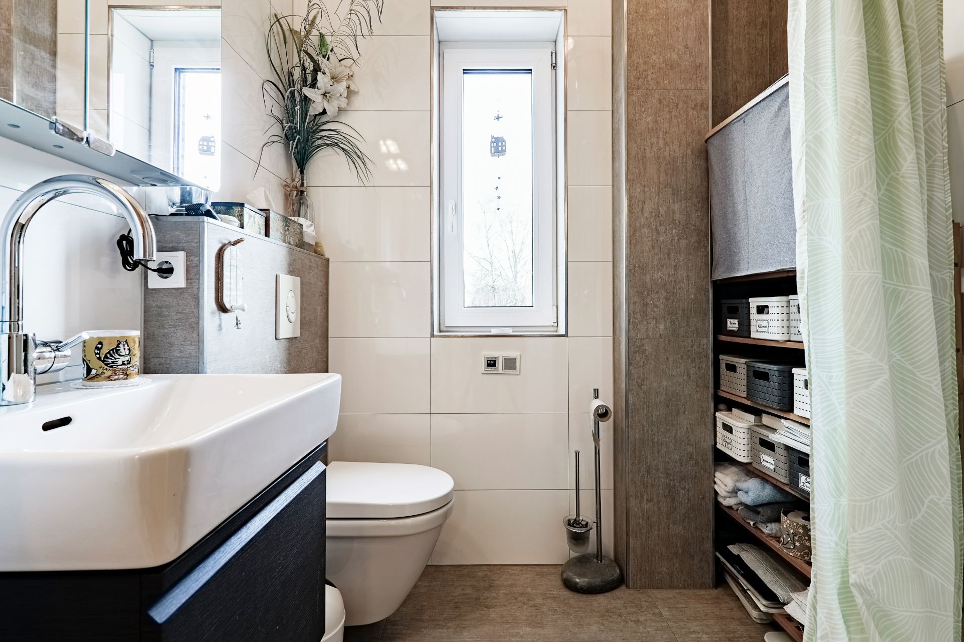 Modernes Badezimmer mit Waschbecken, Toilette, Fenster und Regal mit Aufbewahrungskörben.