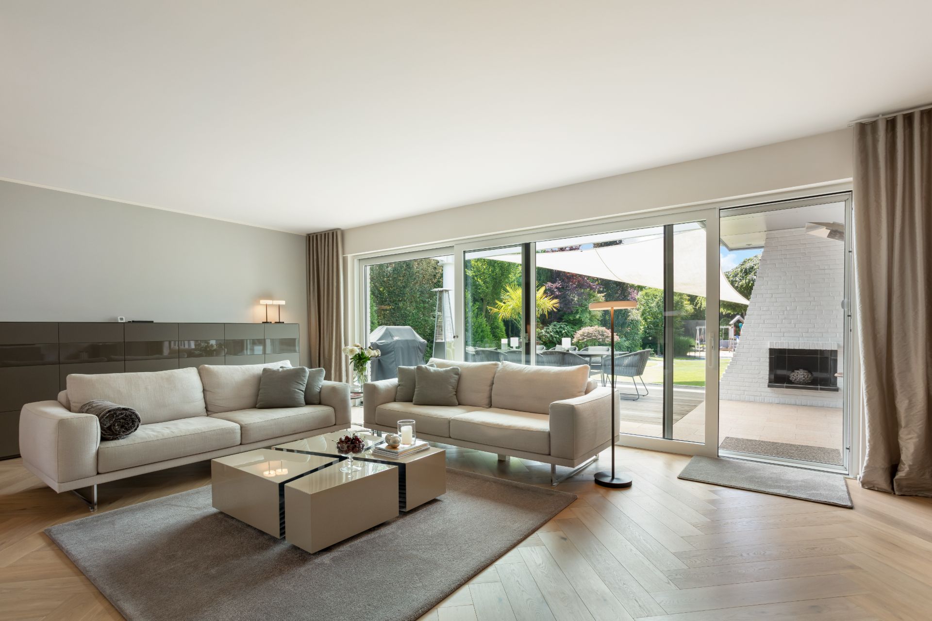 Modernes Wohnzimmer mit zwei Sofas, Couchtisch und großem Fenster mit Blick in den Garten.