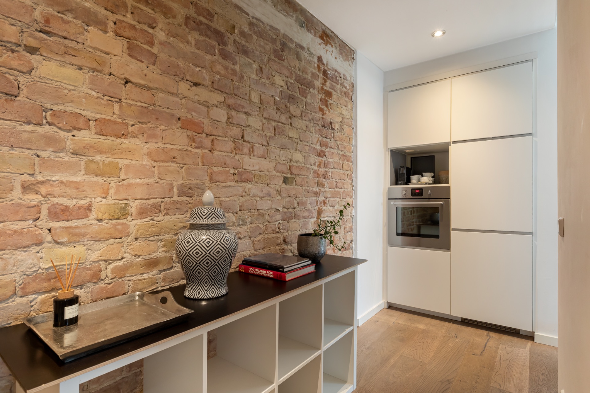 Moderne Küche mit Backofen, offener Regalwand und Ziegelwand.