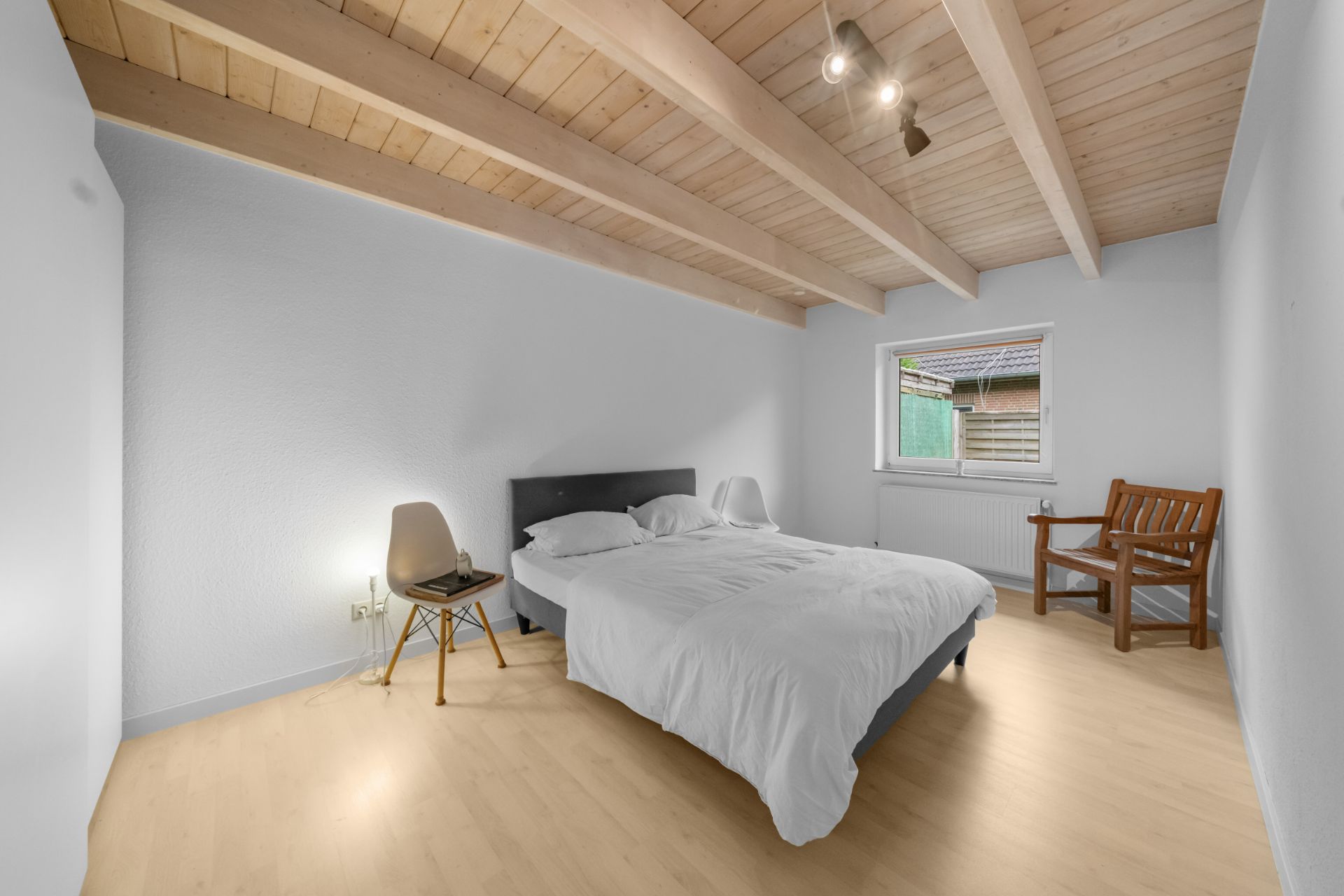 Schlafzimmer mit Doppelbett, zwei Stühlen, Fenster und Holzdecke.
