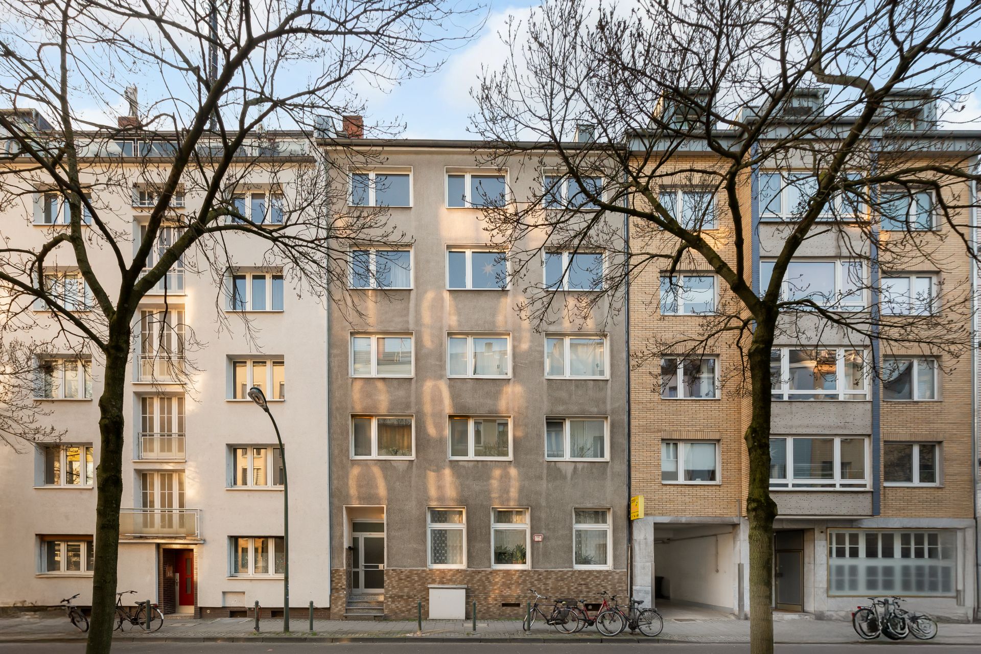 Mehrstöckiges Wohngebäude mit mehreren Fenstern und Fahrrädern vor dem Eingang.