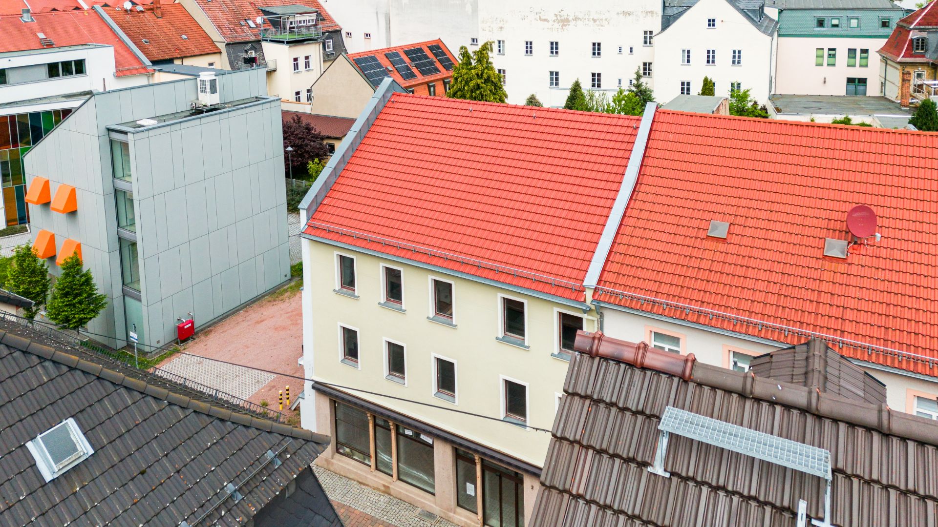 Blick auf Wohnhäuser mit roten Dächern und mehreren Fenstern in einer Stadt.