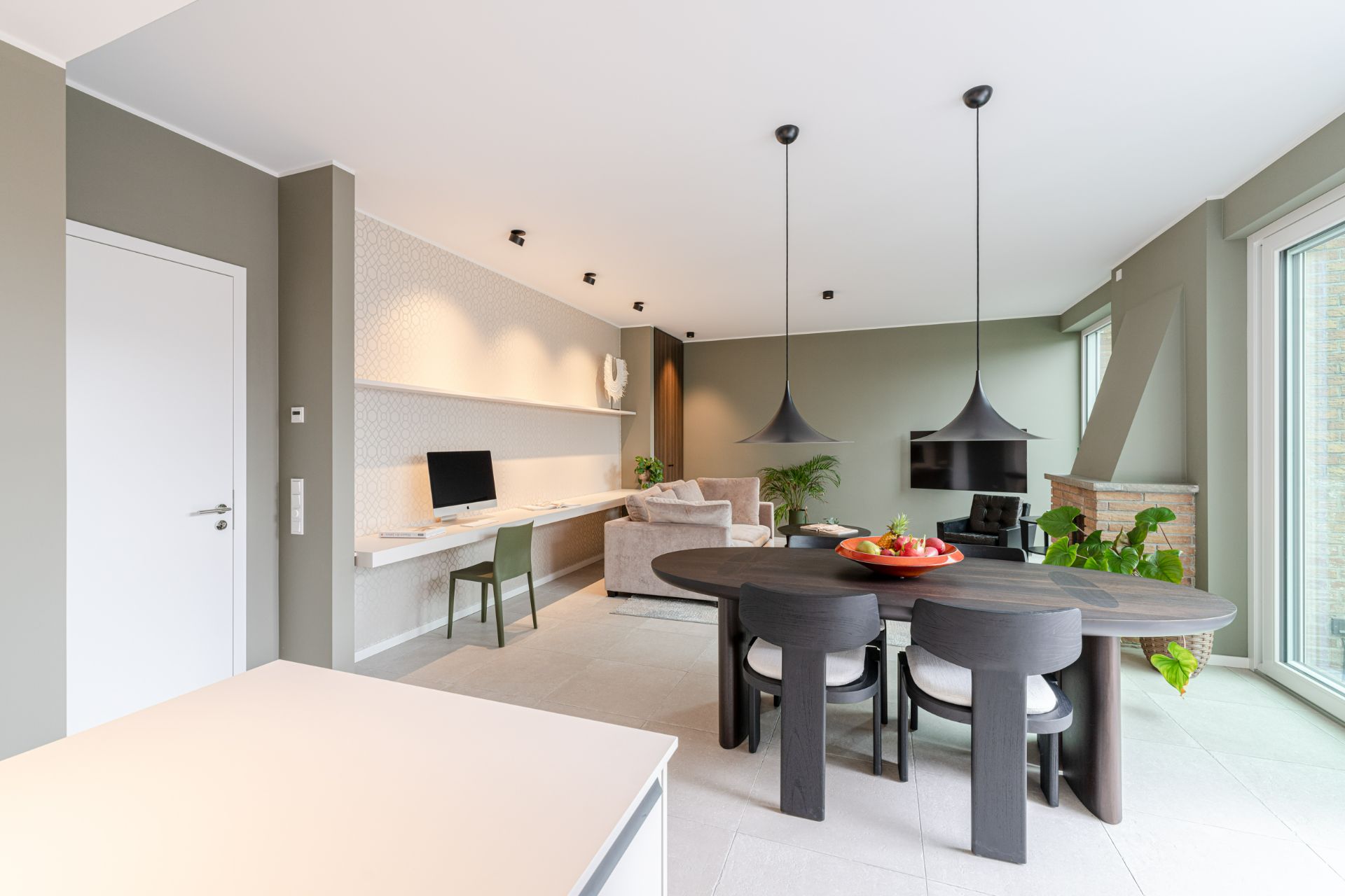 Modernes Wohnzimmer mit Esstisch, Stühlen, Sofa, Schreibtisch und großen Fenstern.