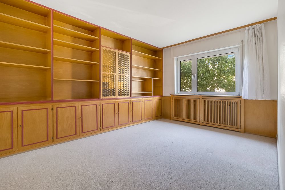 Leerer Raum mit großen Holzregalen und einem Fenster mit Vorhang.