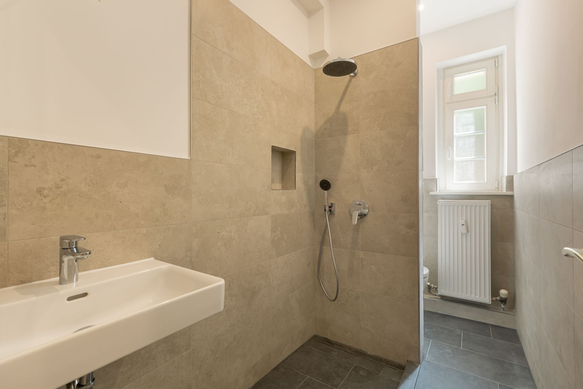 Modernes Badezimmer mit begehbarer Dusche, Waschbecken und Fenster.