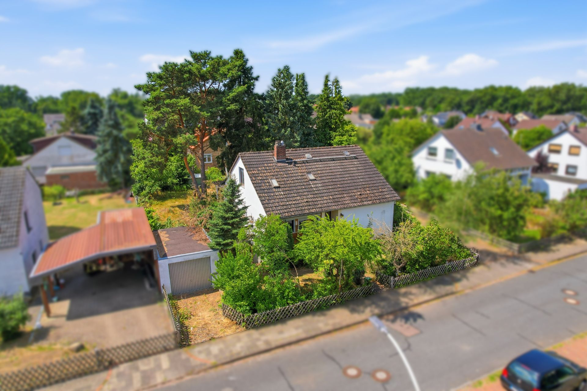 Einfamilienhaus mit Garten, Garage und Carport an einer ruhigen Wohnstraße.