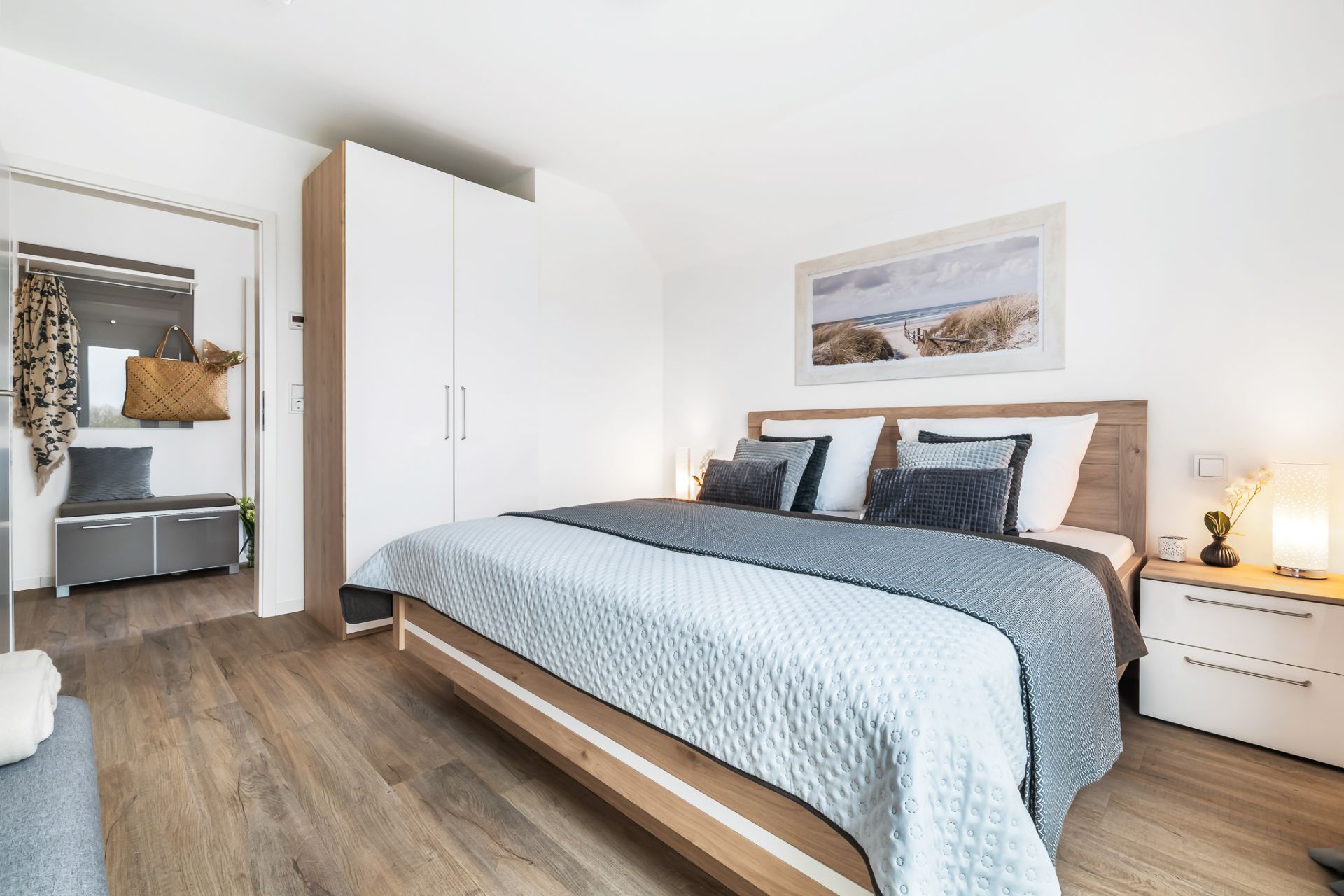 Helles Schlafzimmer mit Doppelbett, Kleiderschrank und Nachttisch, Bild an der Wand.