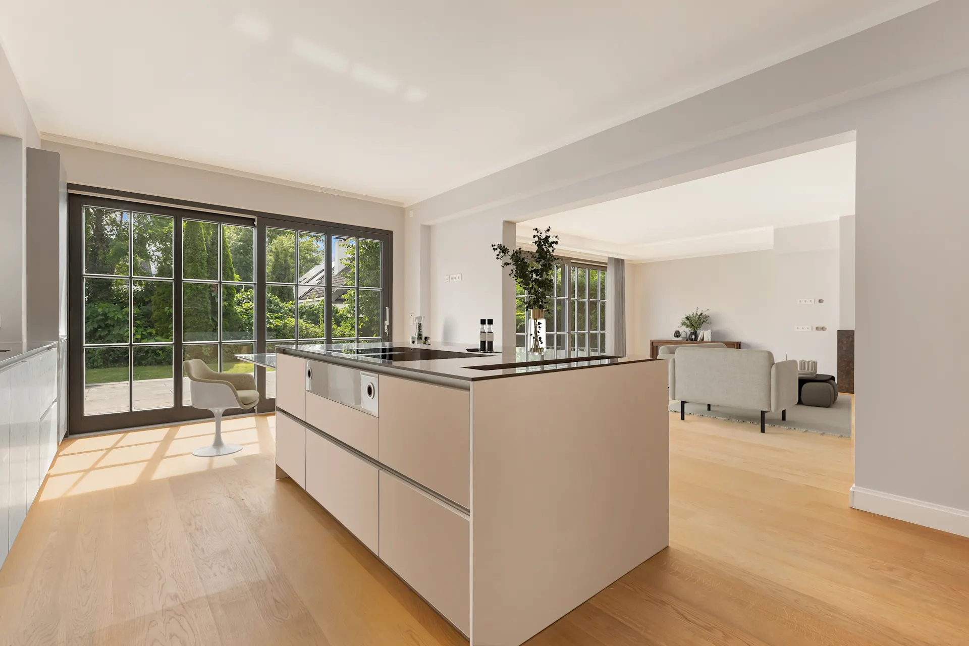 Helles Wohnzimmer mit moderner Küche, Kochinsel und großen bodentiefen Fenstern.