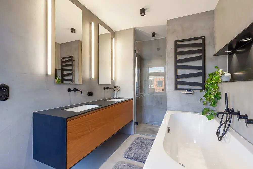 Modernes Badezimmer mit Doppelwaschbecken, Badewanne, Pflanzen und großem Spiegel.