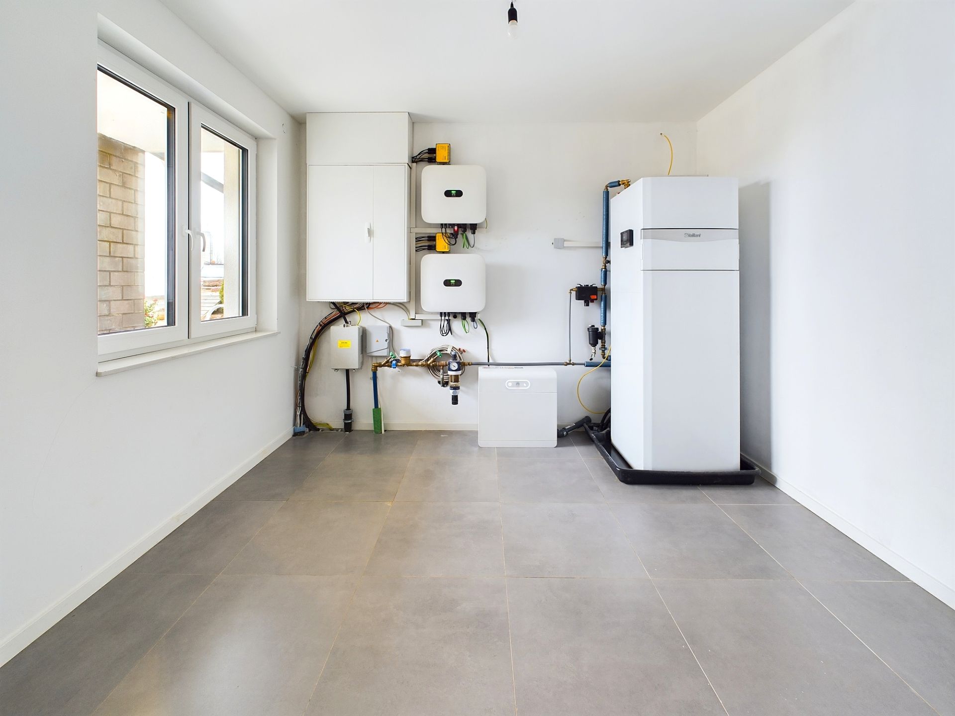 Heller Hauswirtschaftsraum mit moderner Heizungsanlage und großem Fenster.