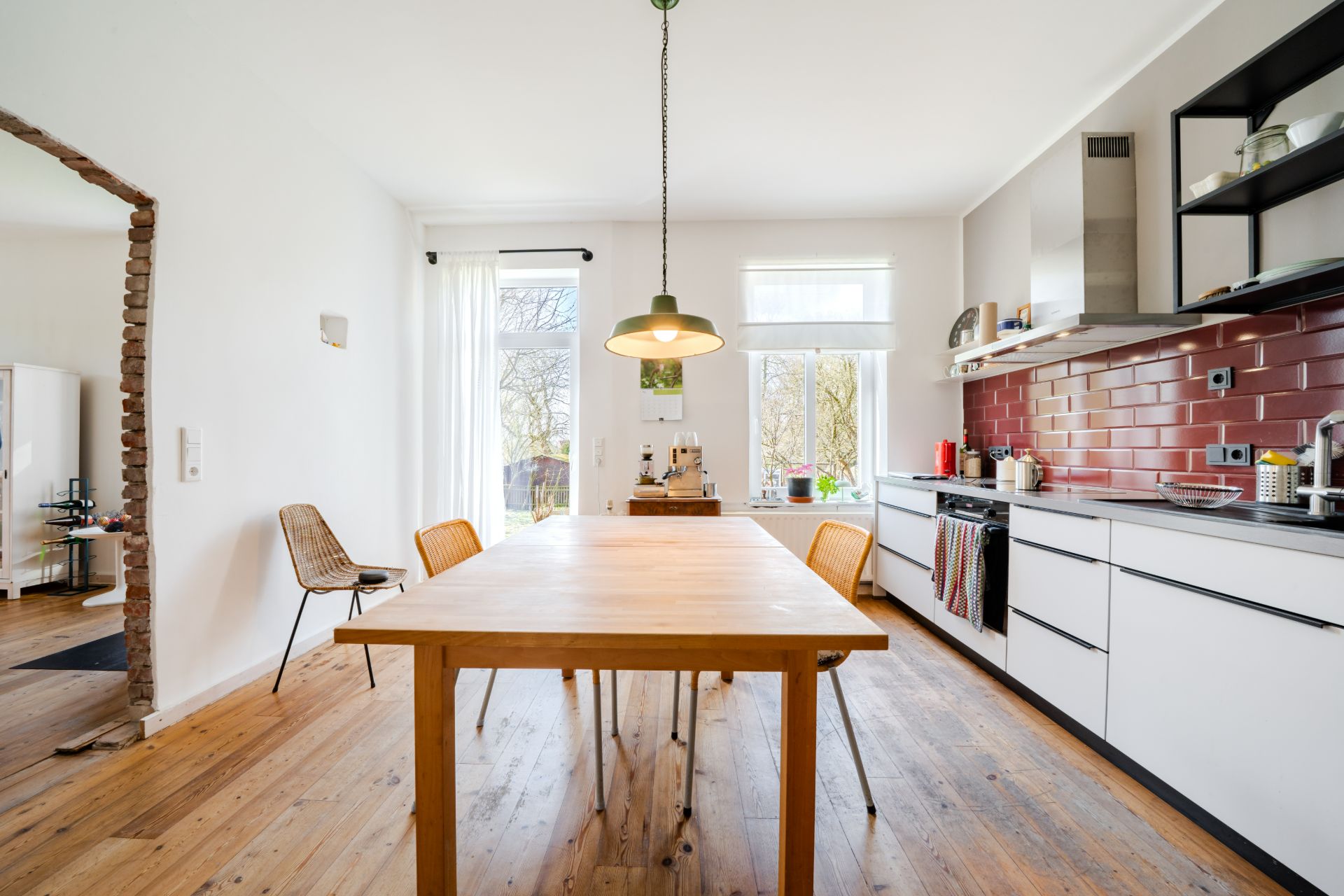 Helle Küche mit Holzboden, Esstisch, Stühlen und moderner Einrichtung.