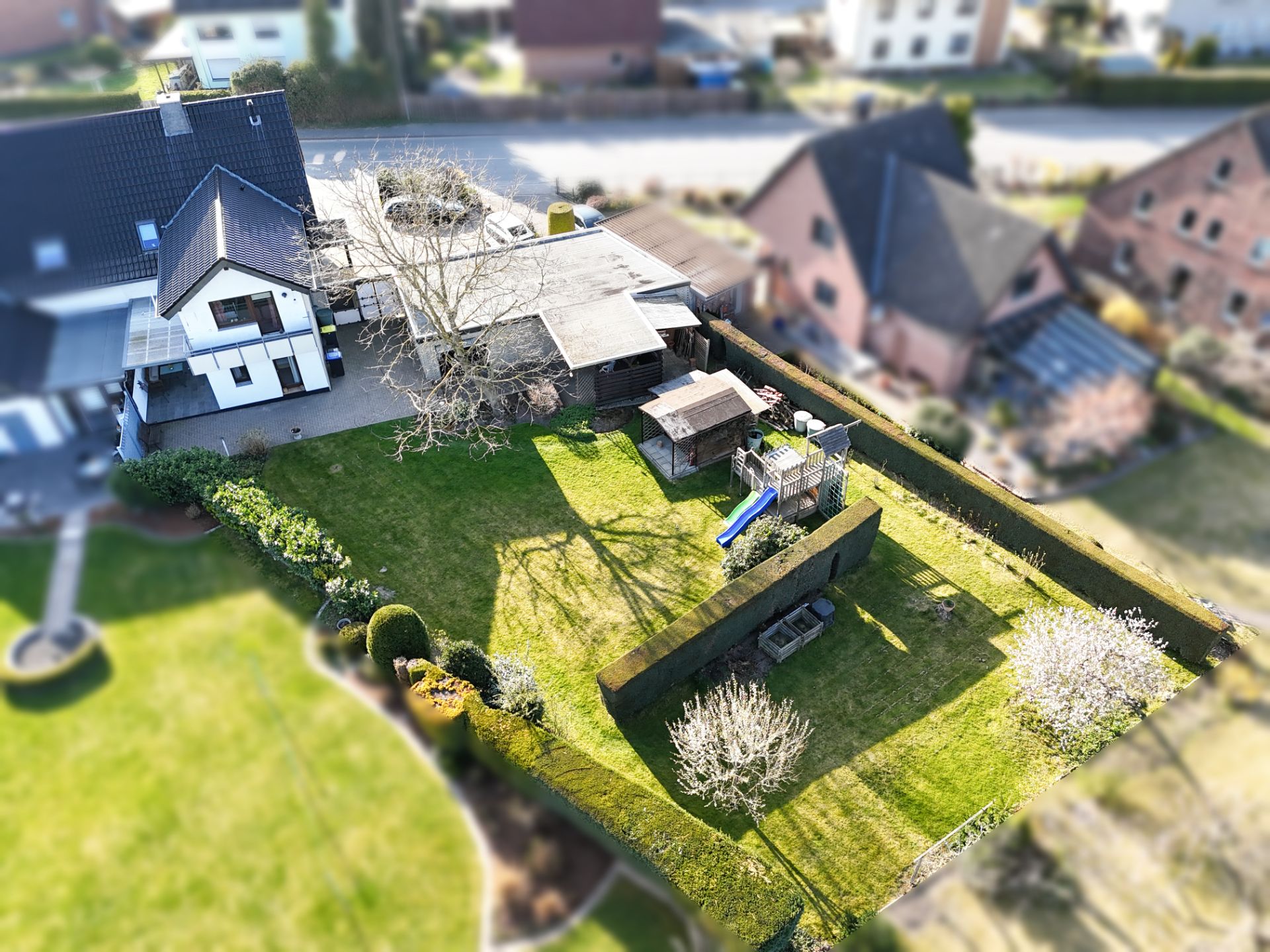 Luftaufnahme von einem Haus mit großem Garten, Spielhaus und Rutsche.