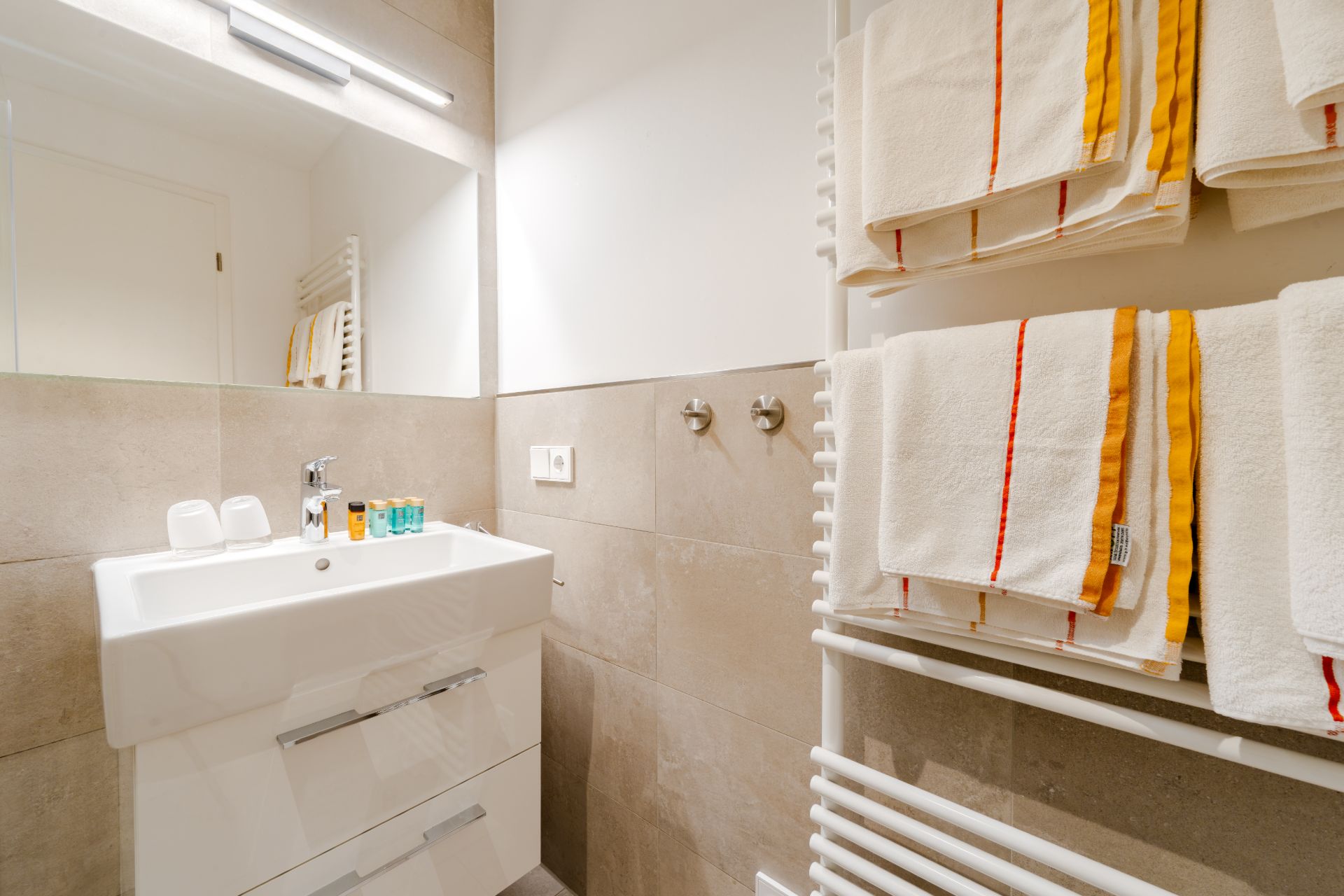 Modernes Badezimmer mit Waschbecken, Spiegel und Handtüchern auf einem Handtuchhalter.